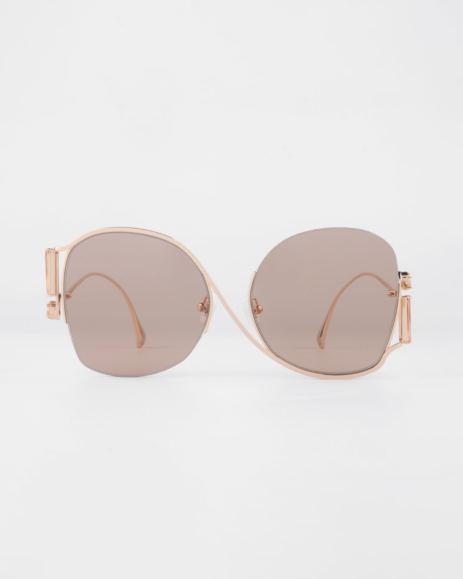 A pair of For Art&#39;s Sake® Sapphire sunglasses with large, light brown lenses and thin, gold-colored frames. The Sapphire sunglasses, offering UV protection, are positioned symmetrically against a plain white background.