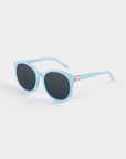 Light blue Scarlett frames with round, dark, shatter-resistant nylon lenses are pictured on a white background. The For Art's Sake® Scarlett sunglasses have a slight cat-eye shape and feature a small decorative gold element on the arms near the UVA & UVB-protected lenses.