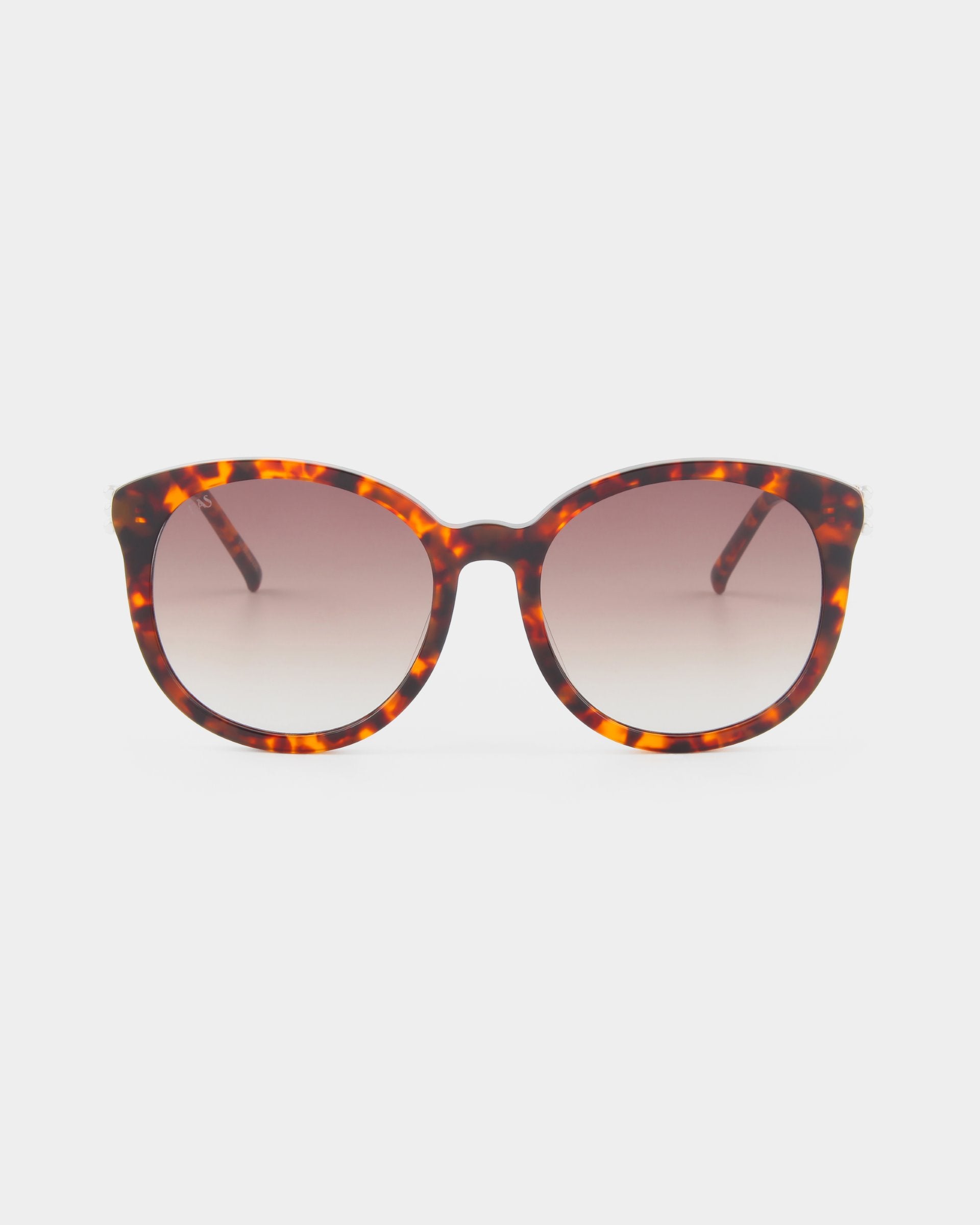 A pair of For Art&#39;s Sake® Scarlett sunglasses with a tortoiseshell patterned frame and round lenses. The ultralightweight shatter-resistant lenses are gradient tinted, transitioning from a darker shade at the top to a lighter shade at the bottom and offering 100% UVA &amp; UVB protection. The background is plain white.