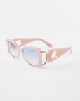 Sculpture by For Art's Sake®: Pink oversized acetate sunglasses with rectangular blue-tinted lenses. The frames feature 18-karat gold-plated accents around the hinges and a decorative gold chain detail on the temples. The arms are thick with a slight curve, offering 100% UVA & UVB protection in a stylishly retro design.