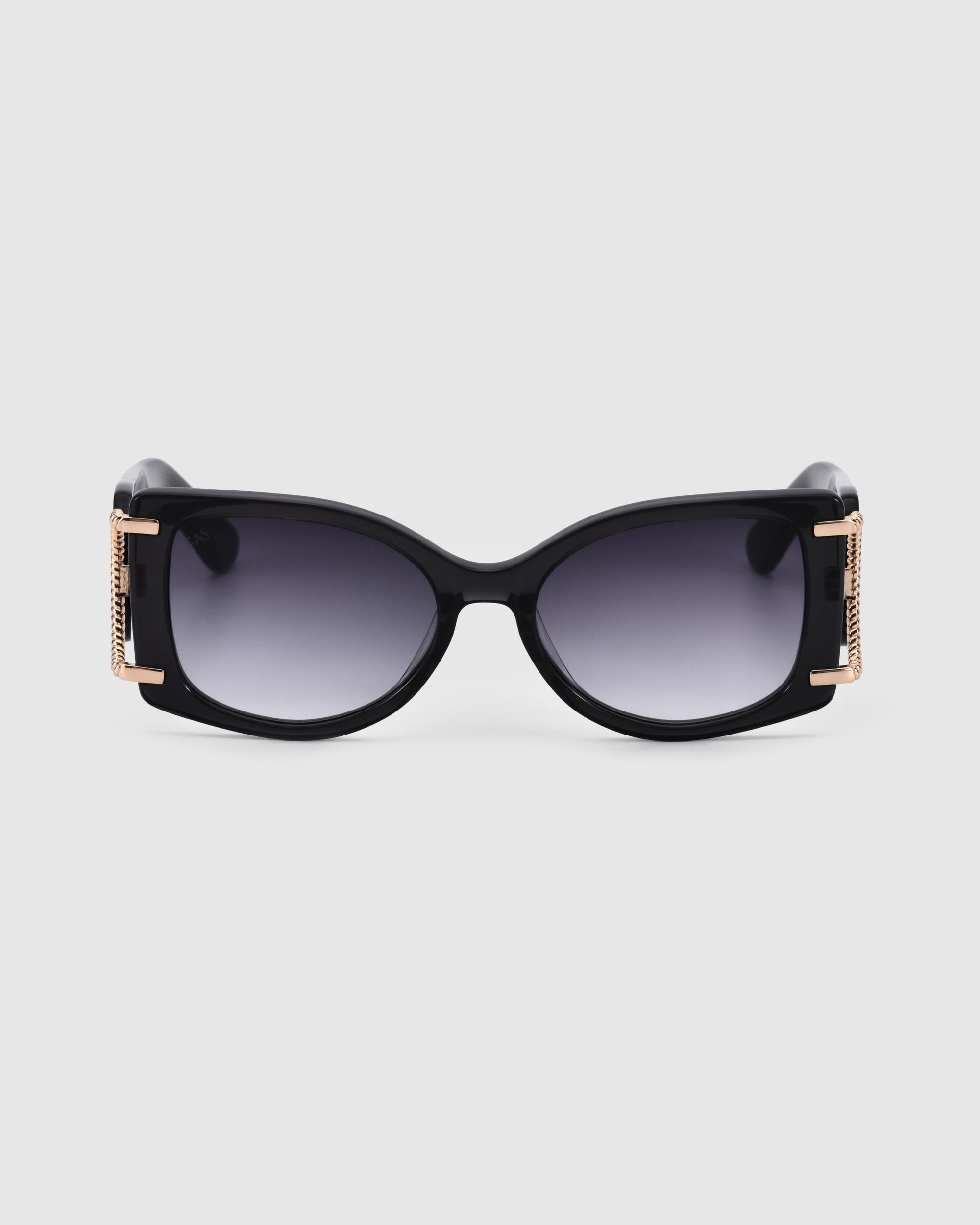 A pair of stylish black sunglasses with dark lenses, featuring gold accents on the temples. These sleek, rectangular, gold-plated Sculpture sunglasses by For Art&#39;s Sake® offer excellent UV protection. The acetate silhouette stands out against the plain white background.