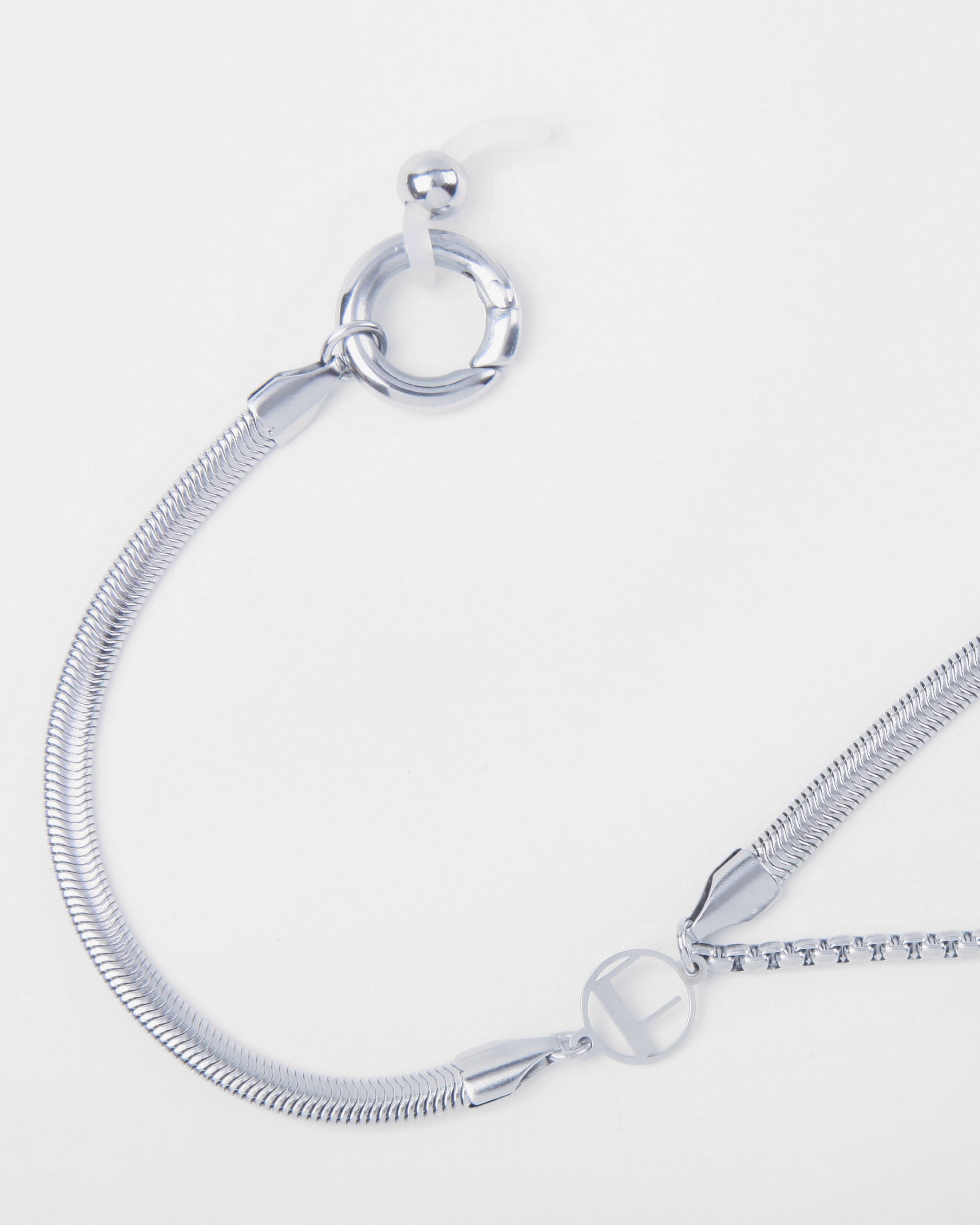 A close-up image of a modern silver Snake Glasses Chain from For Art's Sake® with a multi-strand snake chain design. The Snake Glasses Chain features a toggle clasp system, with one end circular and the other a bar. The sleek, shiny metal reflects light, emphasizing its elegant and contemporary style.