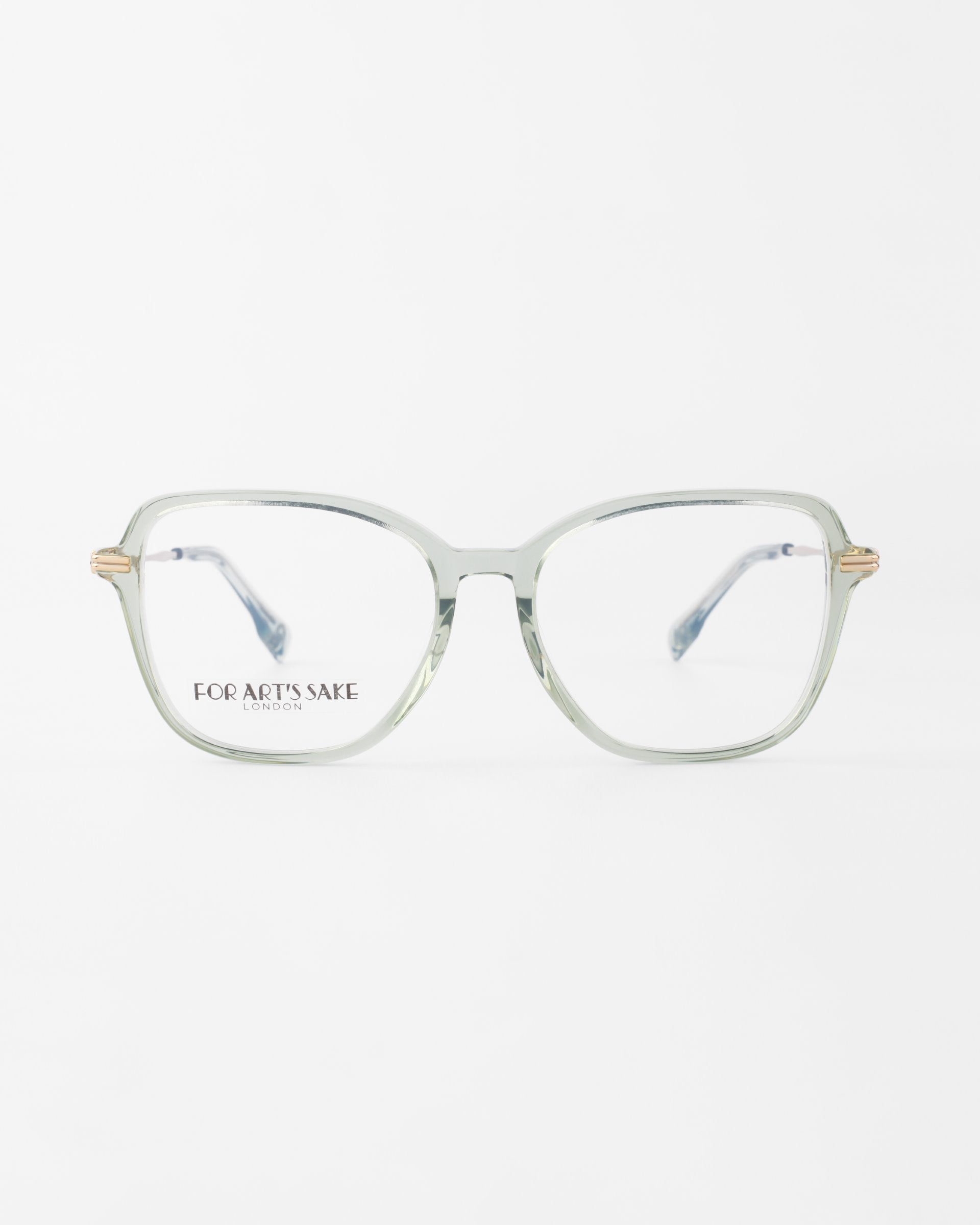 A pair of transparent, square-shaped eyeglasses with thin 18-karat gold-plated arms is displayed on a white background. The words "FOR ART’S SAKE LONDON" are printed on the left lens. These Sonnet frames from For Art's Sake® offer optional prescription lenses and a blue light filter for added protection.