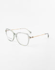 A pair of For Art's Sake® Sonnet glasses with transparent frames and 18-karat gold-plated temples. The glasses have a rounded square shape and clear, prescription lenses, set against a white background.