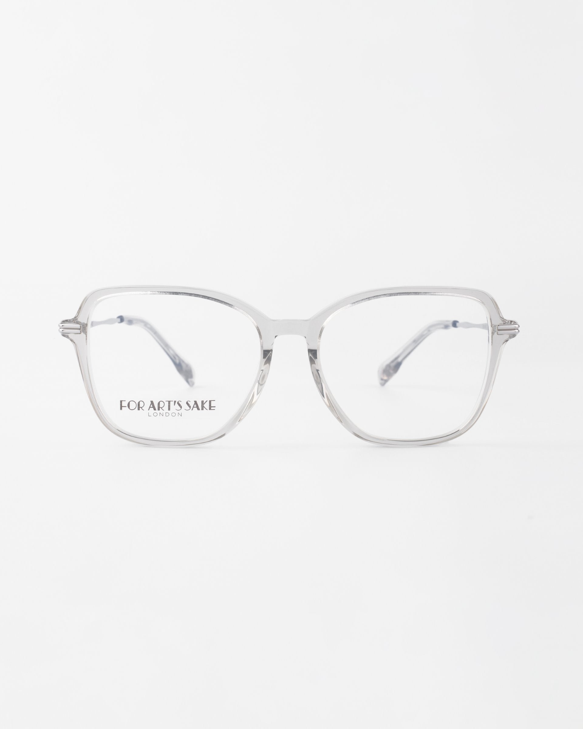 Clear, square-rimmed glasses with a silver metal frame and prescription lenses, inscribed with &quot;For Art&#39;s Sake® London&quot; on the left lens, placed against a plain white background.