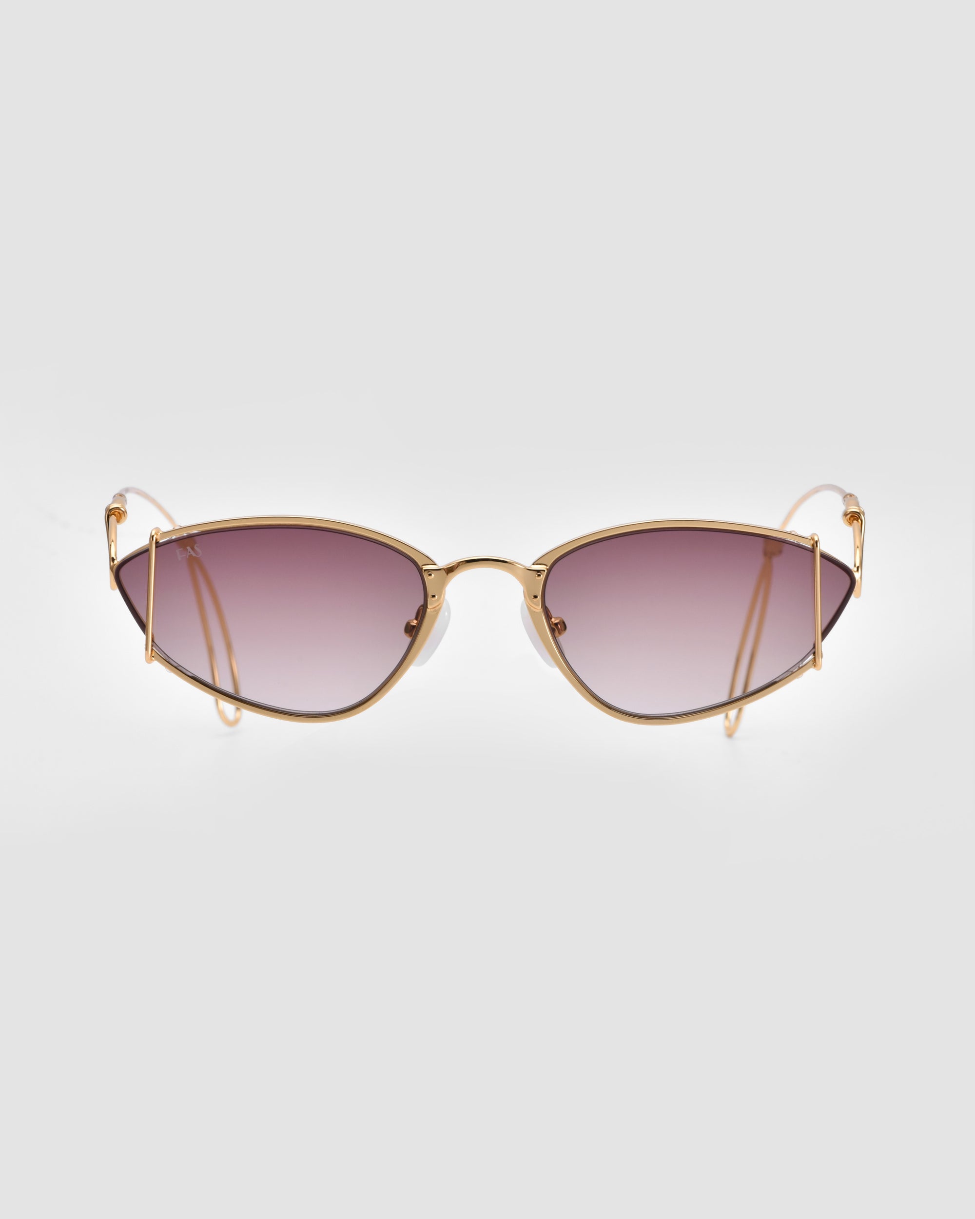 The Ornate sunglasses by For Art&#39;s Sake® are positioned against a plain white background, showcasing their stylish almond-shaped design with gold metal frames and purple-tinted lenses. Featuring a slight cat-eye shape and thin arms, these sunglasses exude a modern and sophisticated appearance while providing 100% UVA &amp; UVB protection.