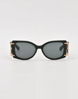 A pair of For Art's Sake® Sculpture black rectangular acetate sunglasses with dark lenses. The arms of the sunglasses feature 18-karat gold-plated accents near the hinges, adding a touch of elegance. These For Art's Sake® Sculpture sunglasses, offering 100% UVA & UVB protection, are set against a plain white background.