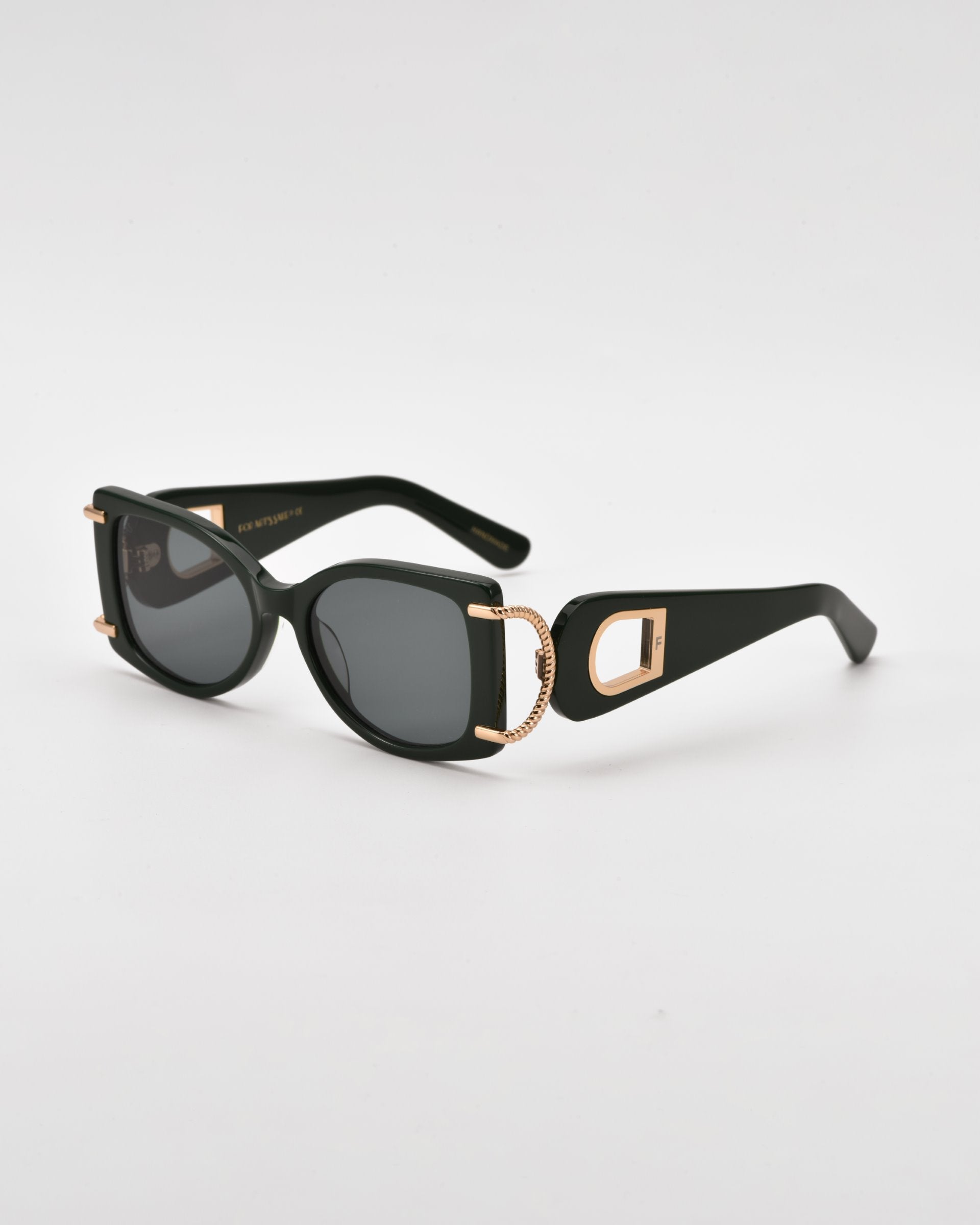 Black rectangular acetate sunglasses with dark lenses featuring 18-karat gold-plated accents on the temples that form a stylish &quot;D&quot; shape. The design includes curved earpieces and offers 100% UVA &amp; UVB protection, presenting a sleek, modern appearance against a plain white background. These are the Sculpture sunglasses by For Art&#39;s Sake®.