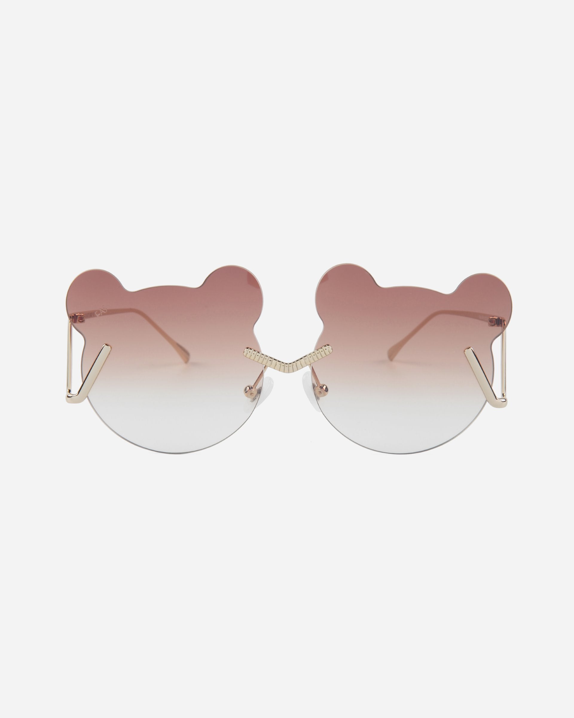 A pair of For Art&#39;s Sake® Teddy sunglasses with unique, bear-ear-shaped frames. The gradient lenses transition from a dark rose color at the top to clear at the bottom. The minimal stainless steel frames feature gold-toned temples and adjustable nosepads for added comfort and UV protection.