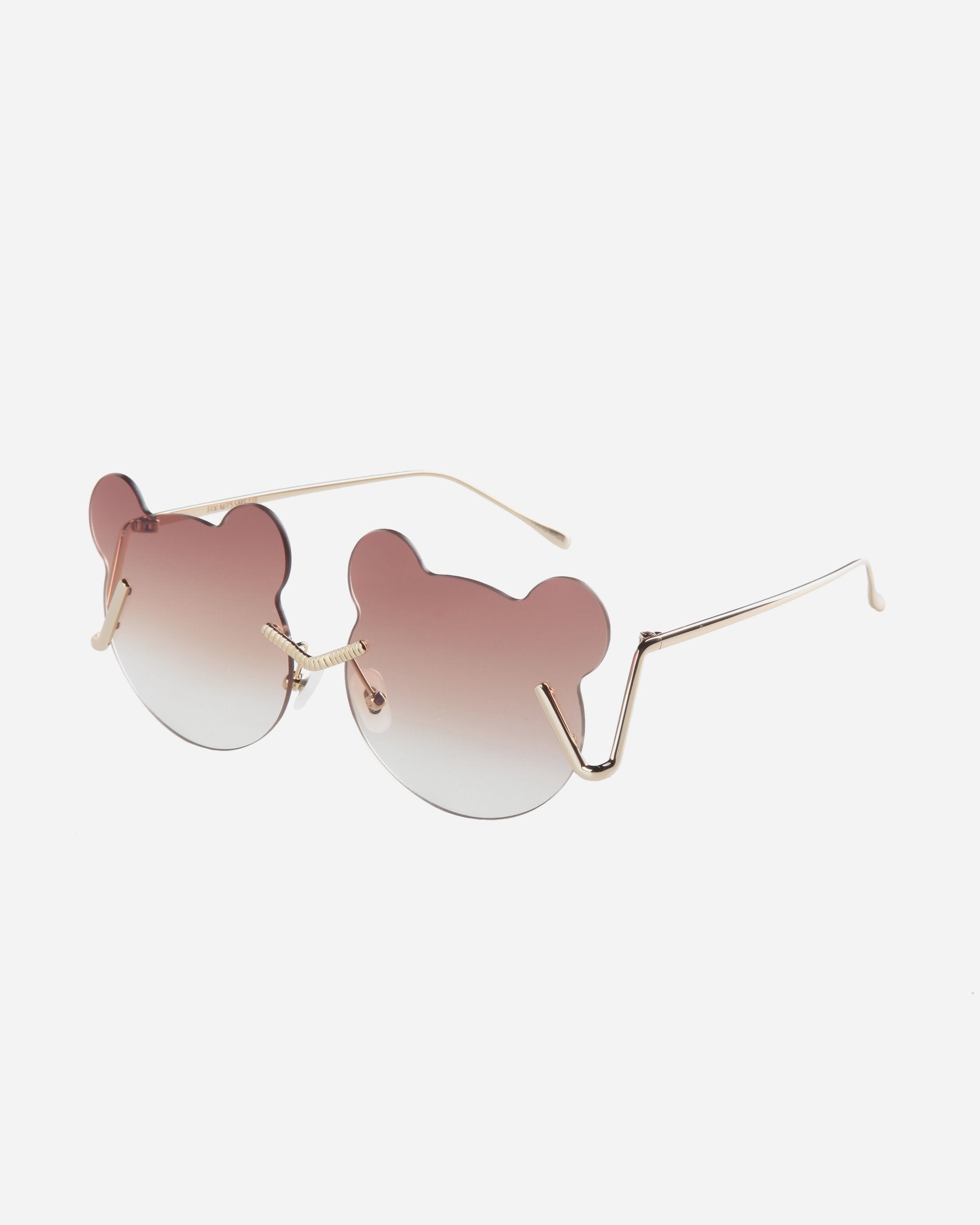 Stylish sunglasses with unique bear-head-shaped lenses featuring a gradient tint from pink to clear and thin, gold-colored stainless steel frames. The ear pieces have a subtle zigzag design near the hinges, and adjustable nosepads ensure comfort. Plus, they offer UV protection for your eyes. The Teddy by For Art's Sake® offers both style and functionality for your eyewear needs.