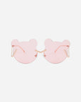 For Art's Sake® Teddy Pink sunglasses are pink, bear-shaped with thin stainless steel arms and no visible frame. The lenses have a light pink tint, offering UV protection, and the nose bridge is designed with small, shiny embellishments. The background is plain white.