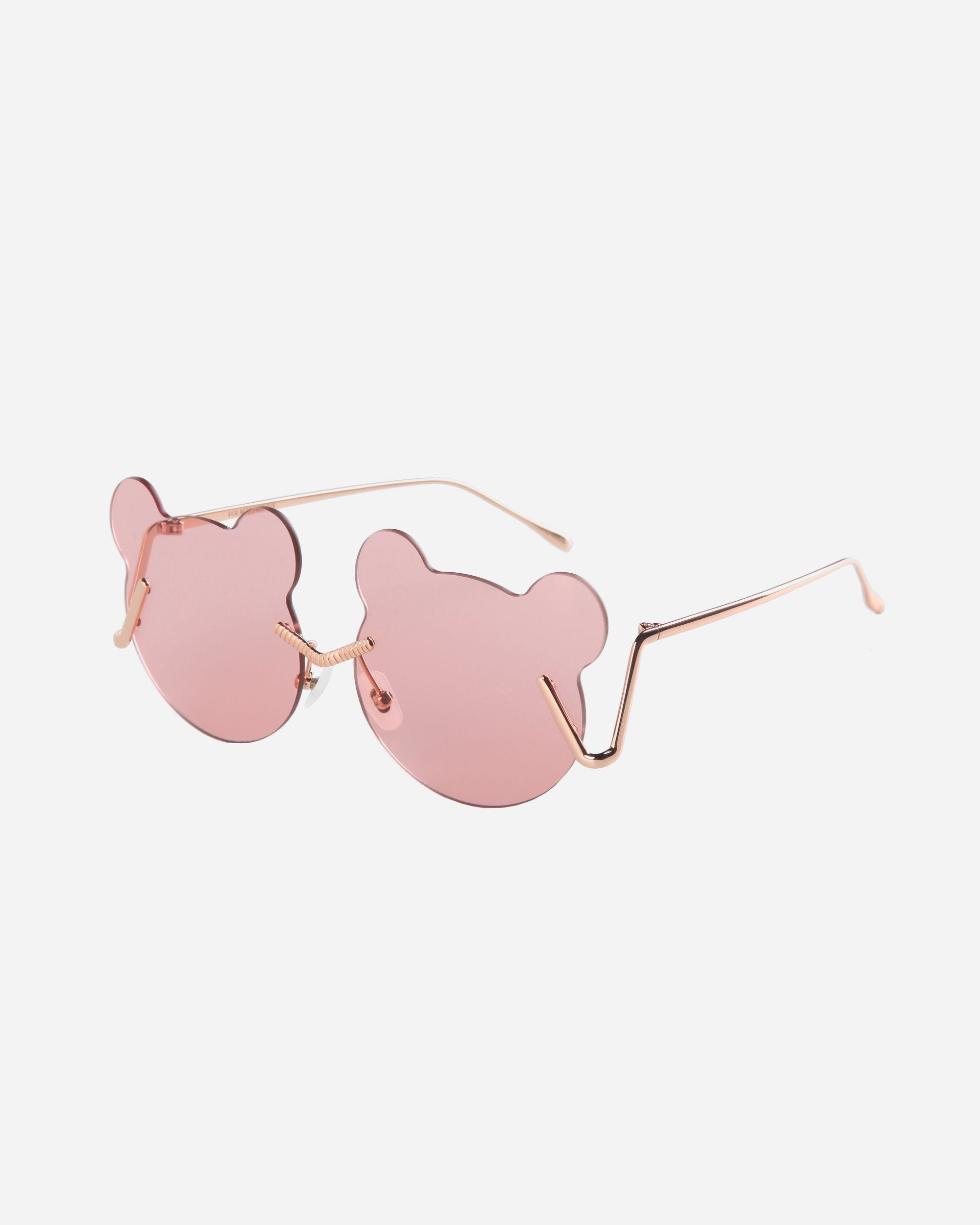 The For Art's Sake® Teddy sunglasses have pink, bear-shaped lenses and thin gold frames on a white background. The temples of the glasses have a slight angular design where they meet the lenses. Featuring UV protection, these stylish shades also come with adjustable nosepads for added comfort and fit.