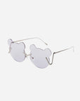 A pair of For Art's Sake® Teddy sunglasses with lenses shaped like bear heads. The lenses offer UV protection and are lightly tinted purple. The frames, made of thin, stainless steel metal, feature adjustable nosepads for comfort. The side arms of the glasses are straight with a slight curve at the ends. The background is plain white.