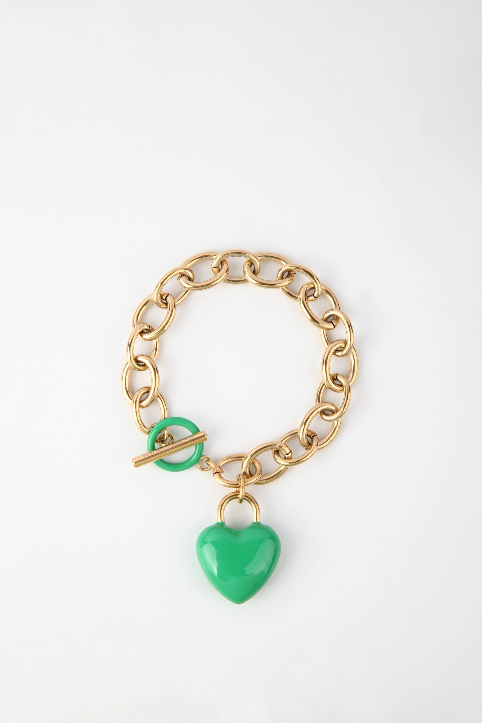A pendant bracelet with large, interconnected 18k gold links is shown on a white background. It features a toggle clasp and an enamel-covered green heart-shaped charm. This is "The Kiss Bracelet" by For Art's Sake®.