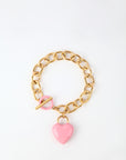 The Kiss Bracelet by For Art's Sake® is crafted with 18k gold, featuring a toggle clasp and an enamel-covered heart charm. The chain boasts large oval links, while the glossy pink heart charm adds a touch of color to the elegant design. Displayed against a plain white background, this piece exudes sophistication.