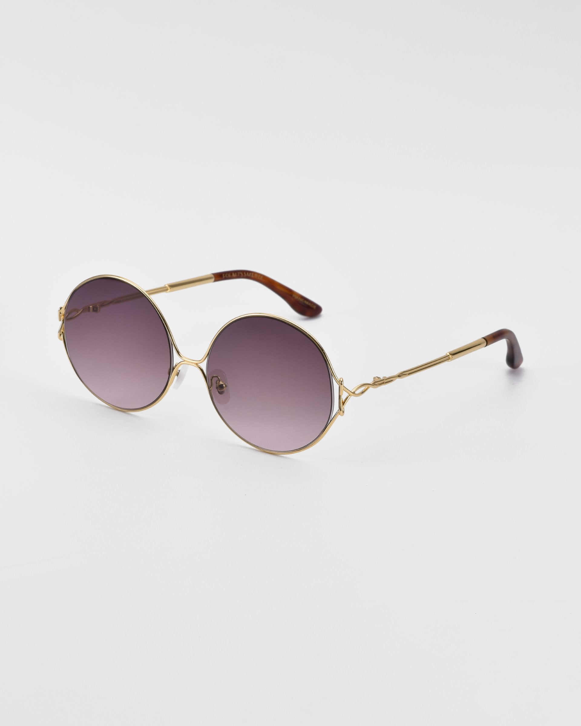 A pair of retro-inspired sunglasses with oversized round frames and a gold metal finish, featuring brown-tinted gradient lenses and tortoiseshell temples. The Aura by For Art&#39;s Sake® is positioned at an angle on a seamless white background.