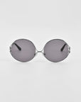 A pair of Aura sunglasses by For Art's Sake® with gradient tinted lenses and thin, silver-colored metal frames. The oversized round frames extend backward, offering a sleek and minimalist design. The sunglasses are set against a plain white background.