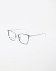 A pair of For Art's Sake® Windsor eyeglasses with a sleek design. The frame is mostly rimless on the bottom, with metallic arms and a thin bridge connecting the lenses. The temples are straight with a transparent section at the tips. The lenses are clear and feature a blue light filter for added protection.