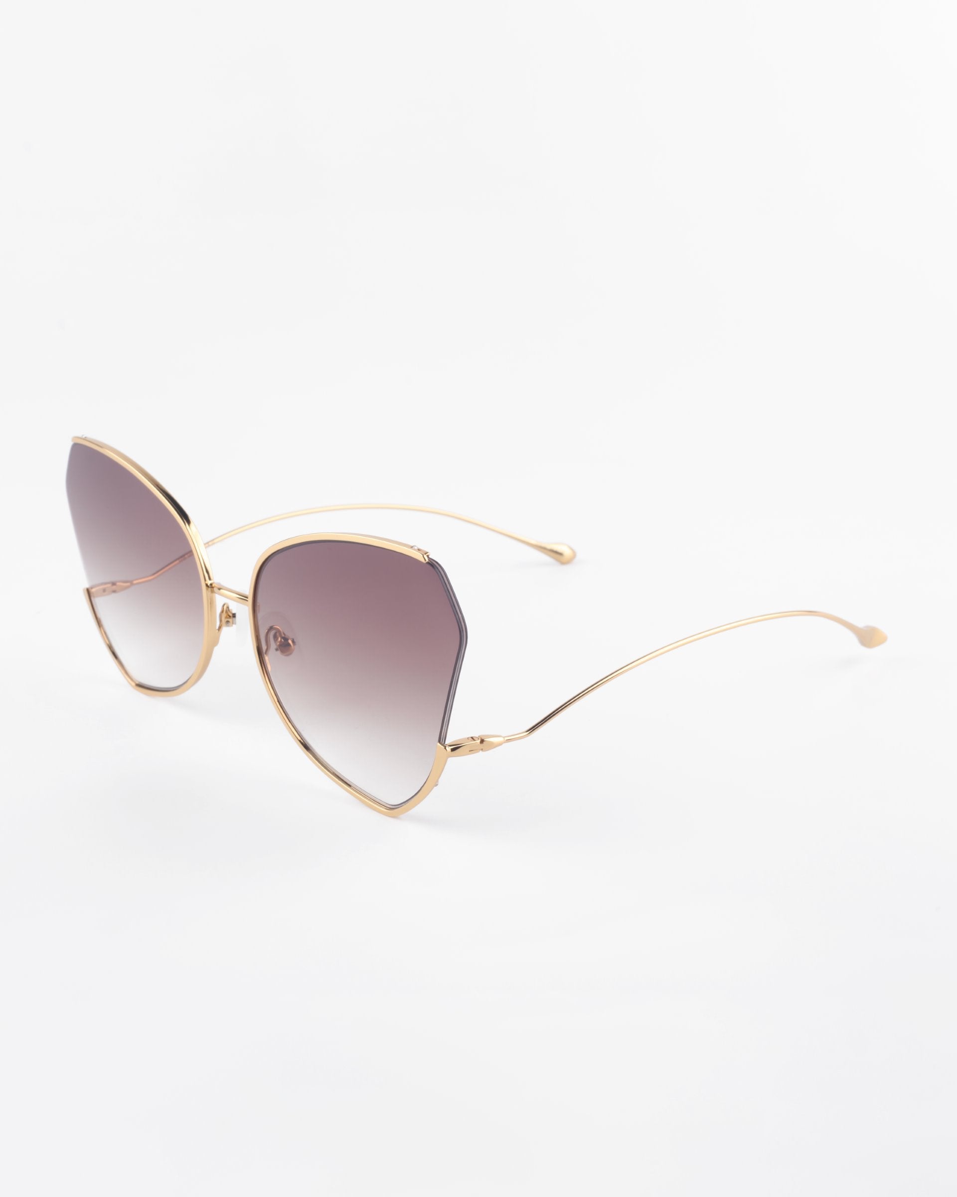 A pair of stylish, hexagon-shaped Watercolour sunglasses from For Art&#39;s Sake® with gold-plated stainless steel frames and gradient brown ombré lenses. The delicate, thin arms of the glasses extend softly, ending in small, curved tips for comfort. The overall design is sleek and contemporary.