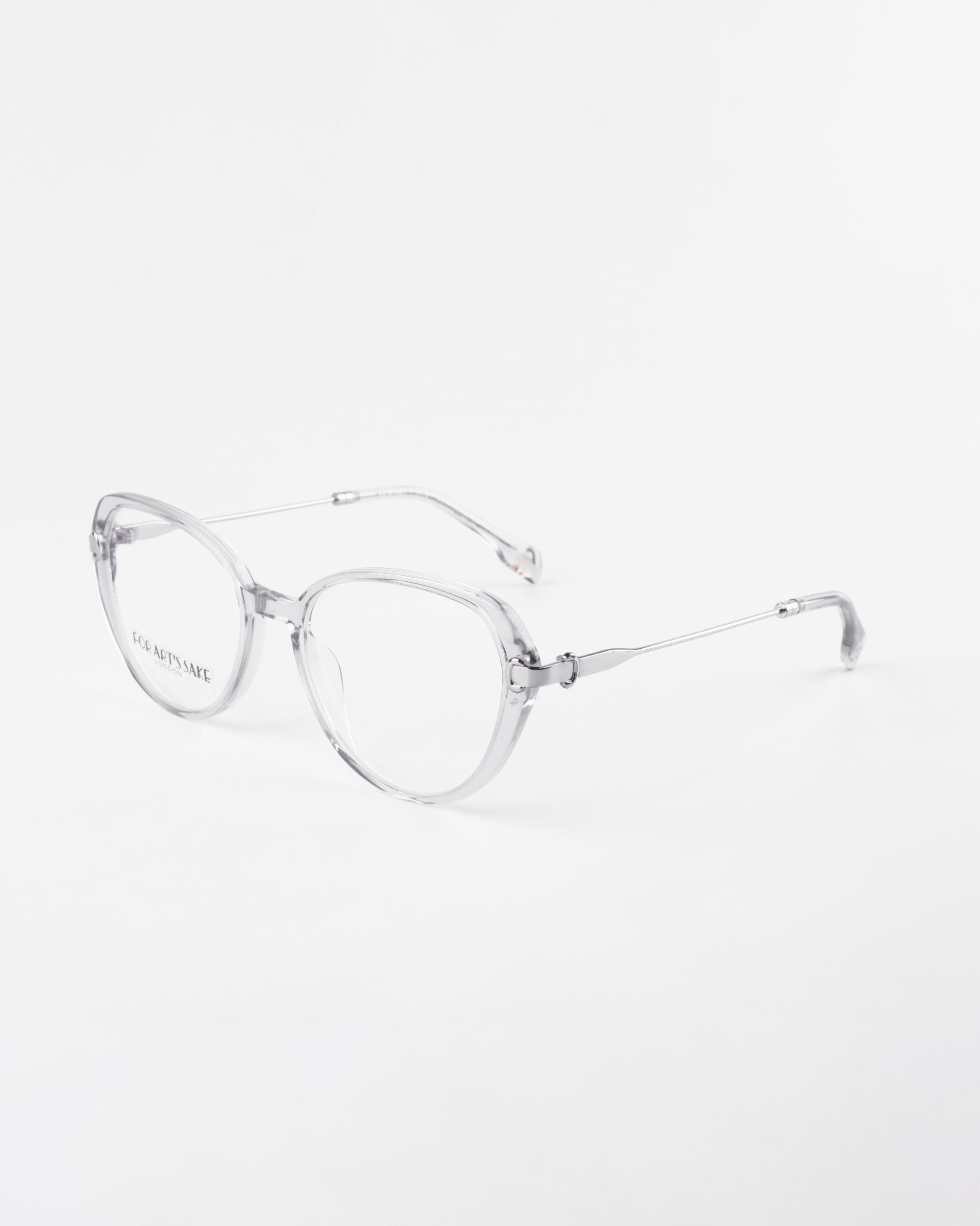 A pair of modern, transparent eyeglasses with round lenses and thin temples. The frame is clear, giving them a minimalist and stylish look. Featuring prescription lenses, the Waterhouse glasses by For Art&#39;s Sake® are set against a plain white background.