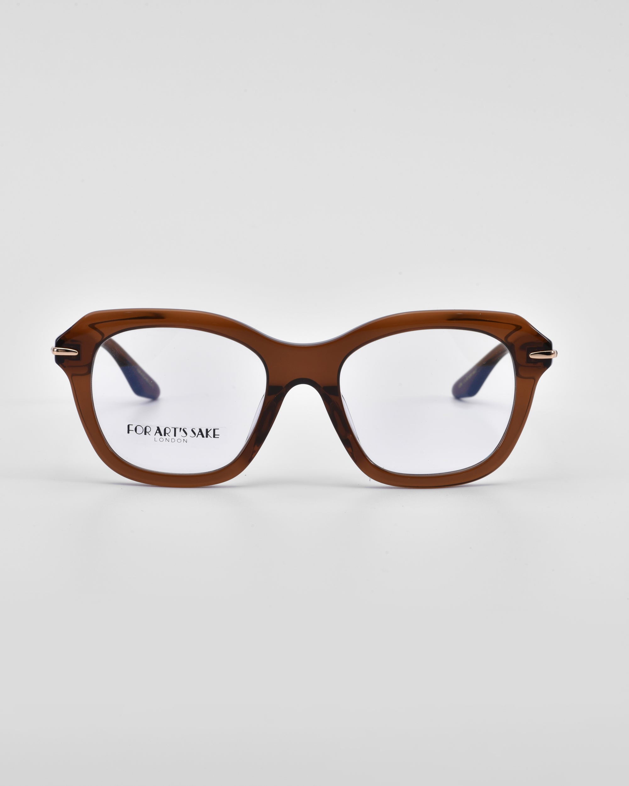 A pair of square-shaped, brown-framed eyeglasses with clear lenses is centered against a white background. The left lens features the brand name &quot;For Art&#39;s Sake®&quot; printed in small black text, showcasing their exquisite craftsmanship in 18-karat gold plating. This particular product is known as the Helene.