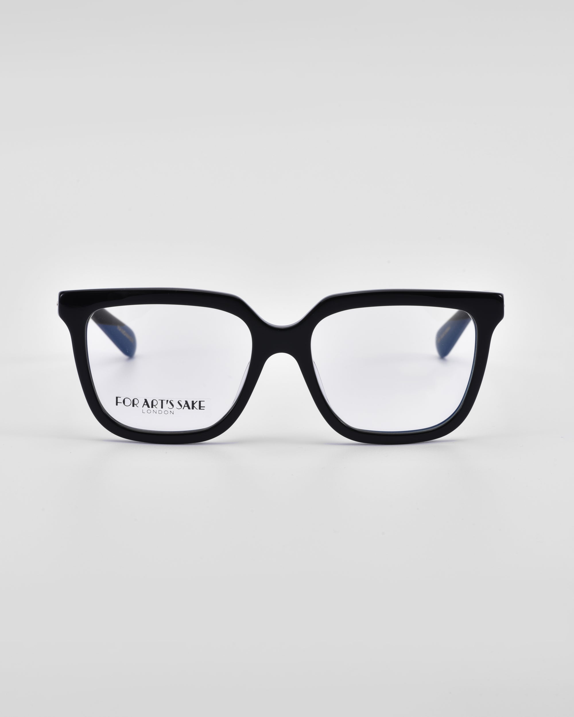 A pair of black-framed eyeglasses with a slightly rectangular, classic square silhouette. The lenses are clear, and the left lens has the text &quot;Nina&quot; and &quot;For Art&#39;s Sake®&quot; printed in black in the lower corner. The background is plain white.
