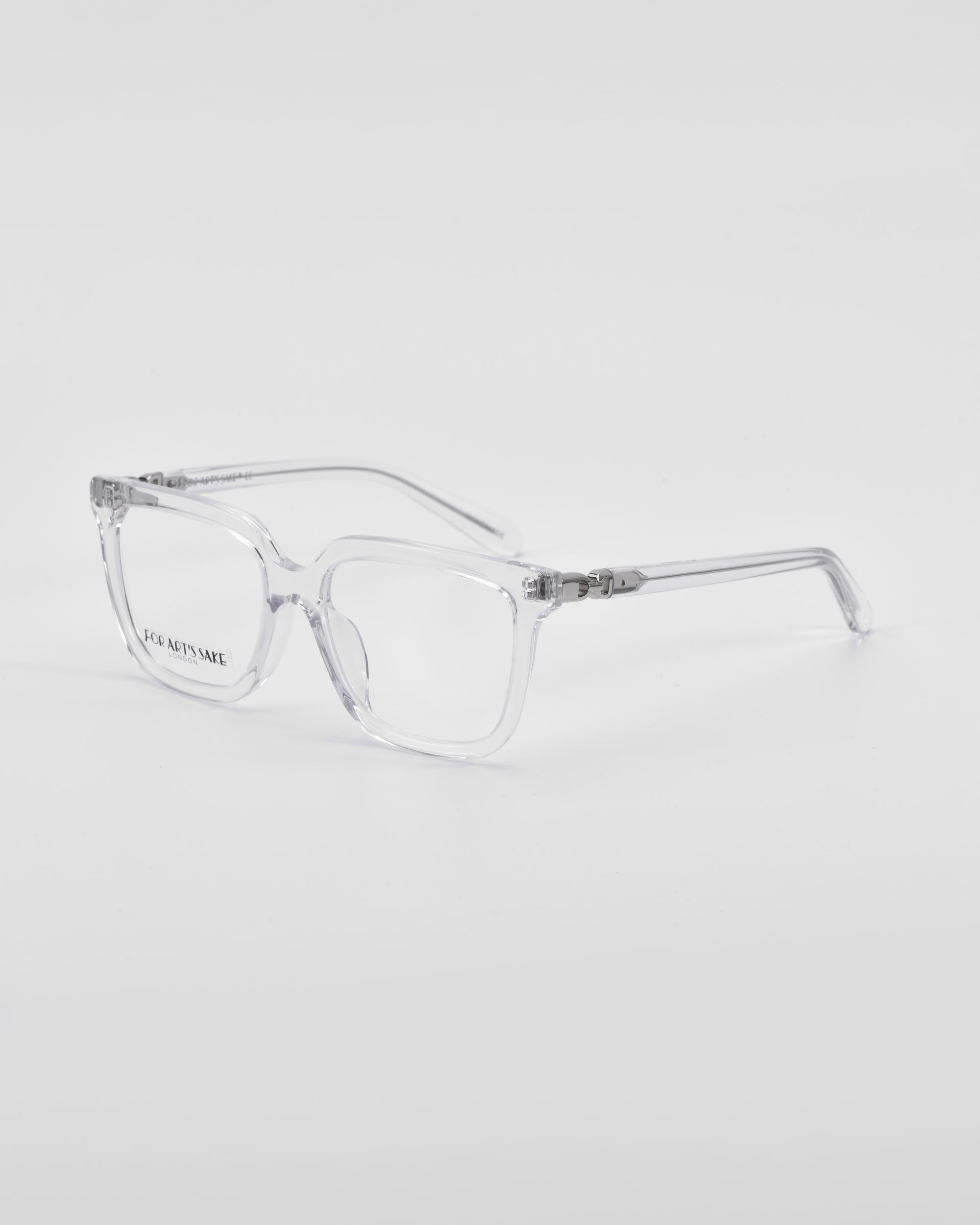 Clear, rectangular-framed eyeglasses with a classic square silhouette are displayed against a plain white background. The lenses have a slight tint, and the temples attach to the frame with small metal hinges. These stylish Nina frames by For Art&#39;s Sake® can be customized through our prescription service to meet your vision needs.