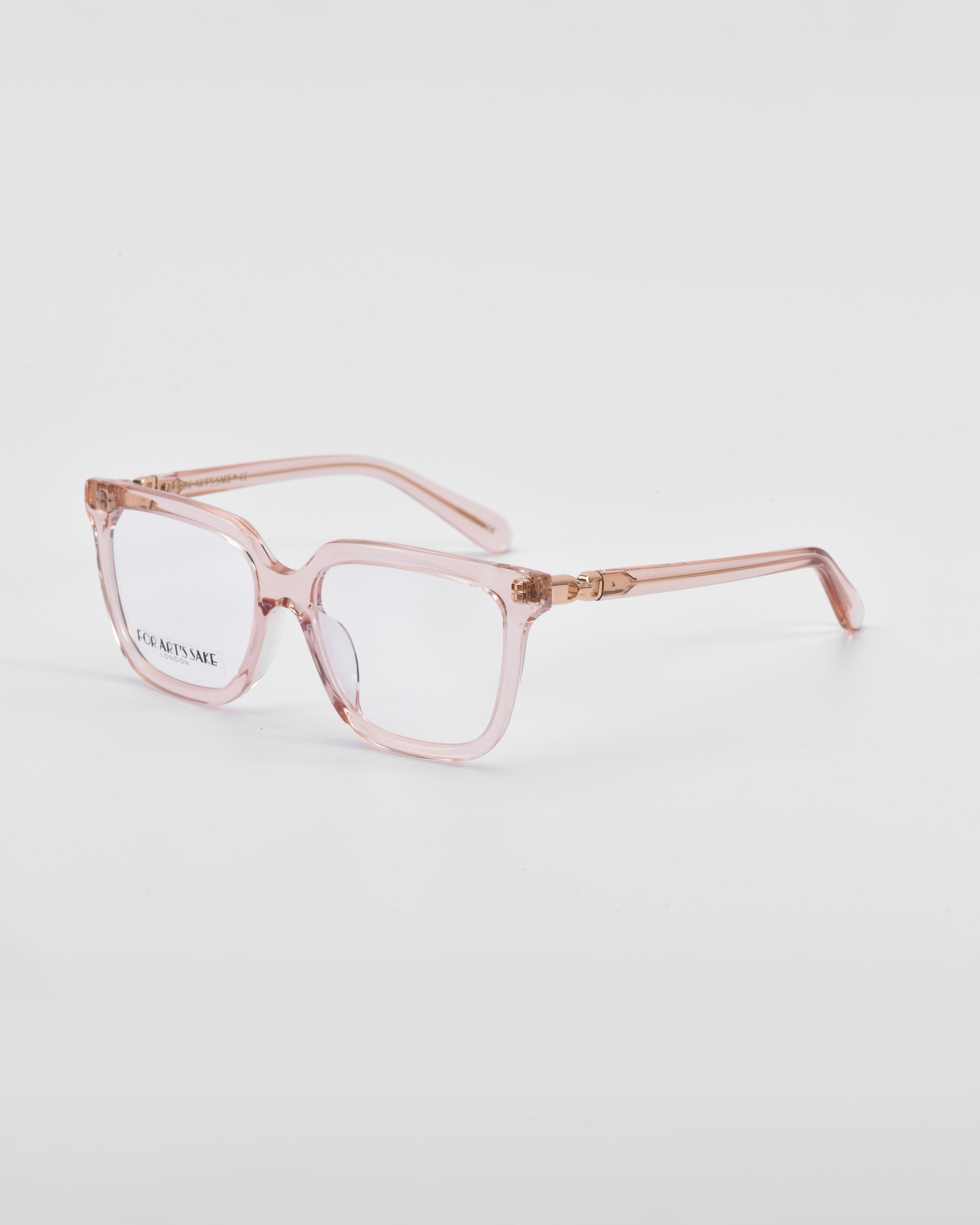 A pair of stylish square-framed eyeglasses with transparent pink frames sits on a plain white background. The classic square silhouette is complemented by clear lenses and temples featuring subtle 18-karat gold hinges, adding a touch of elegance to the Nina by For Art&#39;s Sake®.