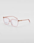 A pair of stylish square-framed eyeglasses with transparent pink frames sits on a plain white background. The classic square silhouette is complemented by clear lenses and temples featuring subtle 18-karat gold hinges, adding a touch of elegance to the Nina by For Art's Sake®.