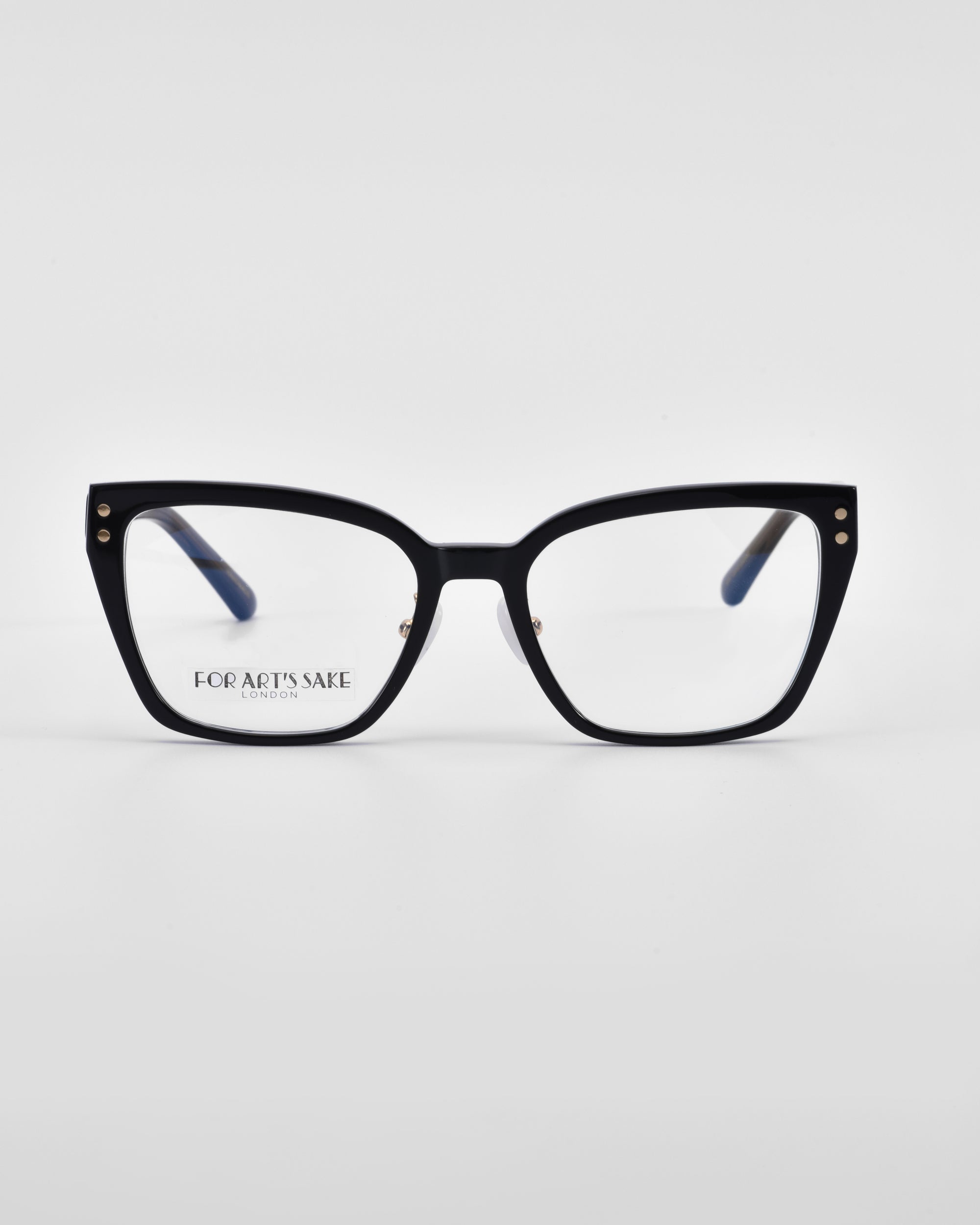 A pair of black-framed eyeglasses with a geometric shape, slightly angled at the corners, resembling cat-eye opticals. The lenses are clear, and the words "For Art's Sake®" are visible on the inside of the left lens. The background is a plain white.