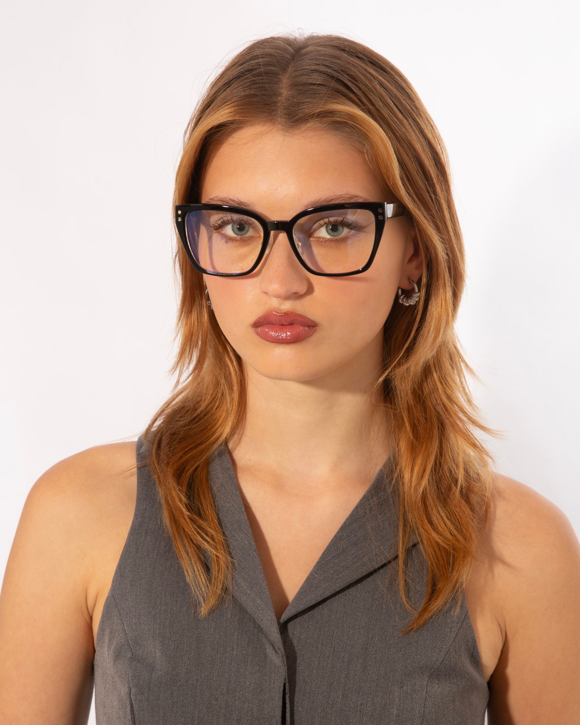 A person with long, light brown hair is wearing black-rimmed glasses and a gray sleeveless top. The Abbey by For Art&#39;s Sake® frames their neutral expression perfectly, set against a plain white background.