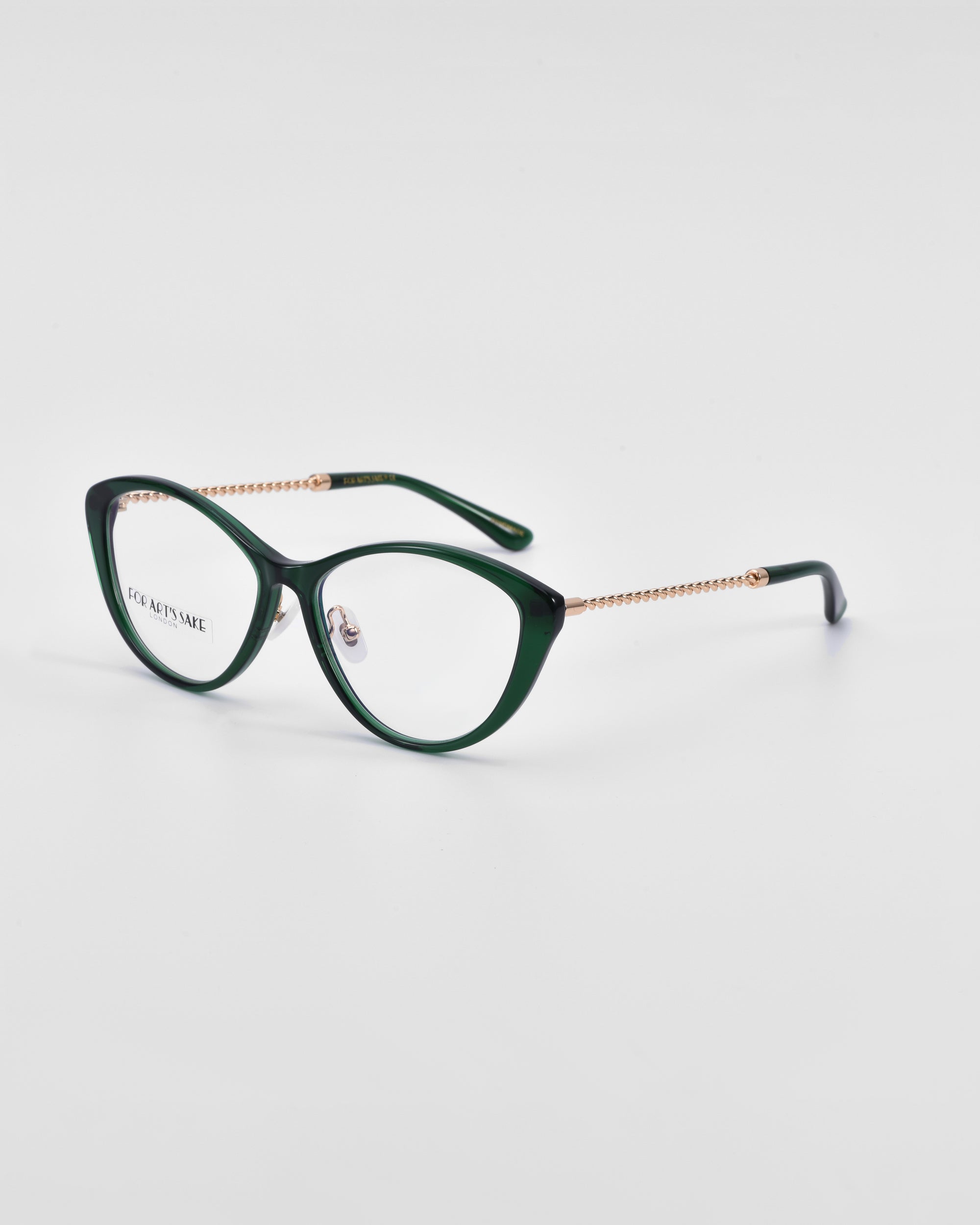 A pair of dark green Perla II eyeglasses with a cat-eye shape, positioned on a white background. The temples of the glasses are adorned with a gold chain-like pattern and 18-karat gold plating. The inside of the right lens is inscribed with &quot;For Art&#39;s Sake®,&quot; highlighting their exquisite optical design.