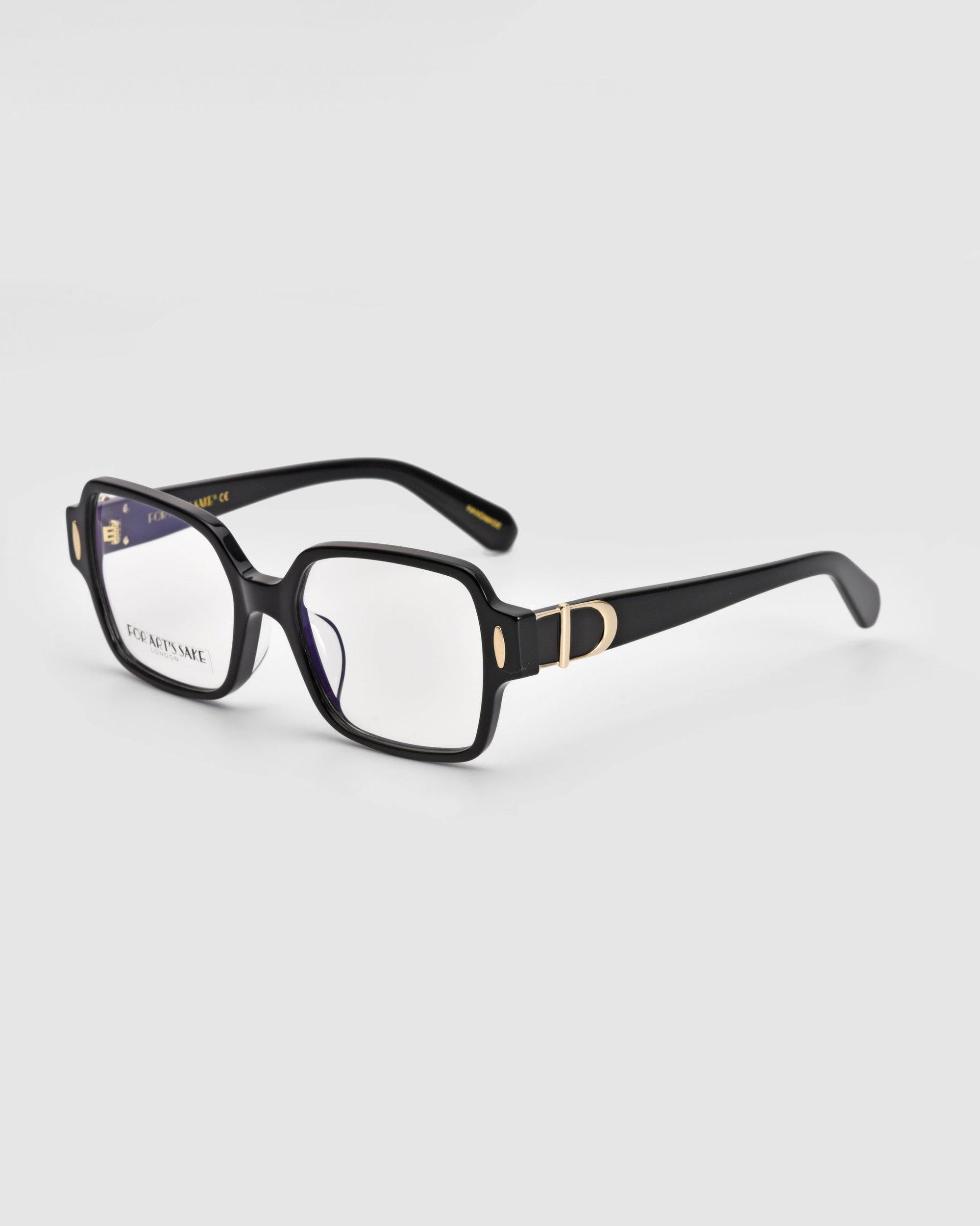 A pair of Hart eyeglasses by For Art&#39;s Sake® featuring a black rectangular frame with gold-accented temples. These versatile glasses come with clear lenses, and the inner side of the arms displays an unreadable text or logo against a plain white background.