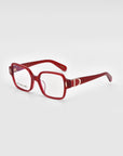 A pair of Hart eyeglasses by For Art's Sake®, featuring red rectangular frames with clear lenses and thick design. The temples boast a decorative silver accent near the hinges. These classic glasses are displayed on a white surface with the right temple extended outward.