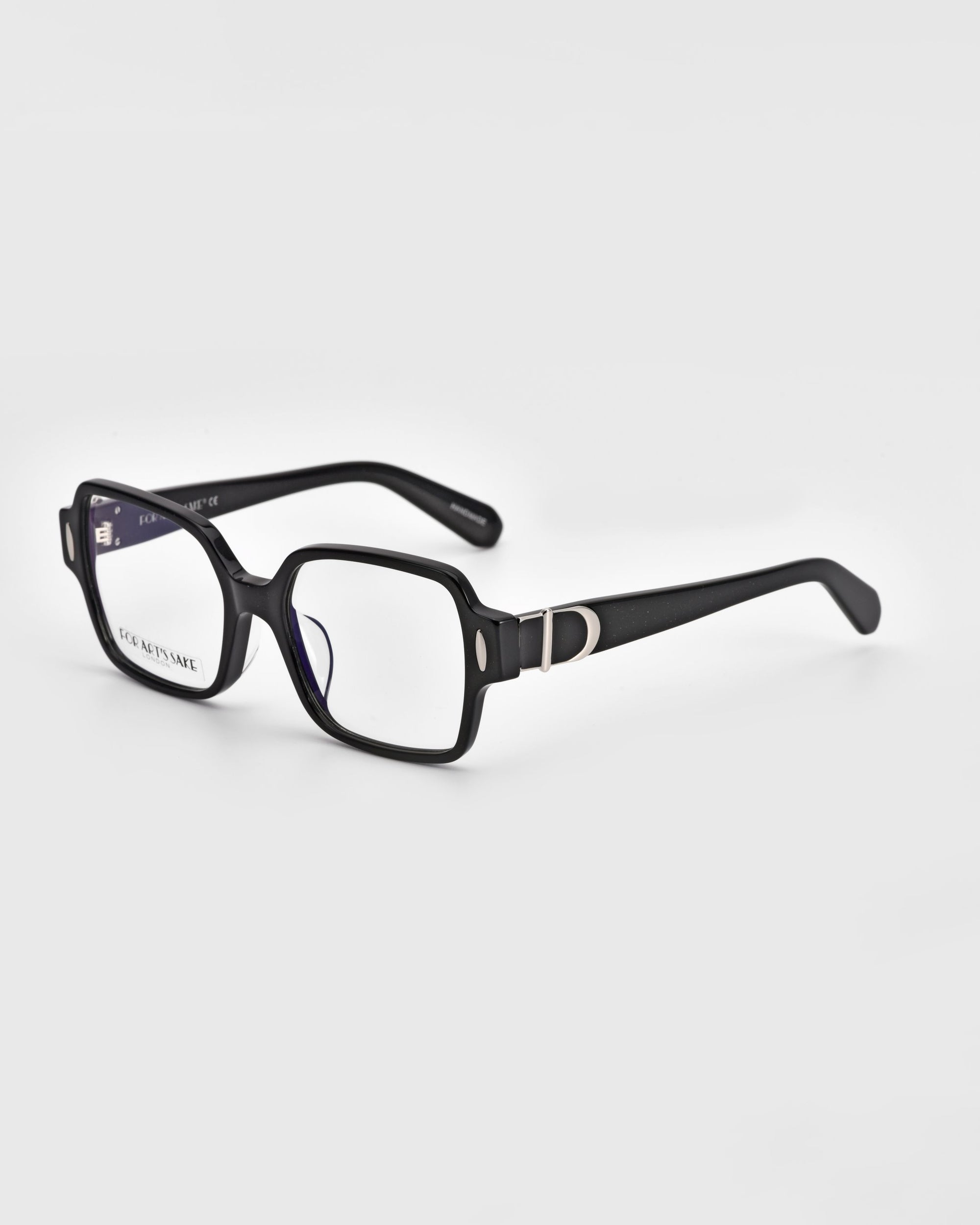 A pair of Hart eyeglasses by For Art&#39;s Sake® with black frames and rectangular lenses is displayed against a white background. The arms feature a distinct silver &quot;D&quot; accent near the hinges, highlighting their classic design.