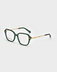 The Delight by For Art's Sake® are a pair of stylish square eyeglasses with a dark green, square-shaped frame and gold-toned temples featuring unique details. The arms have black tips. The lenses are clear, and the overall design marries modern sophistication with a touch of vintage charm.