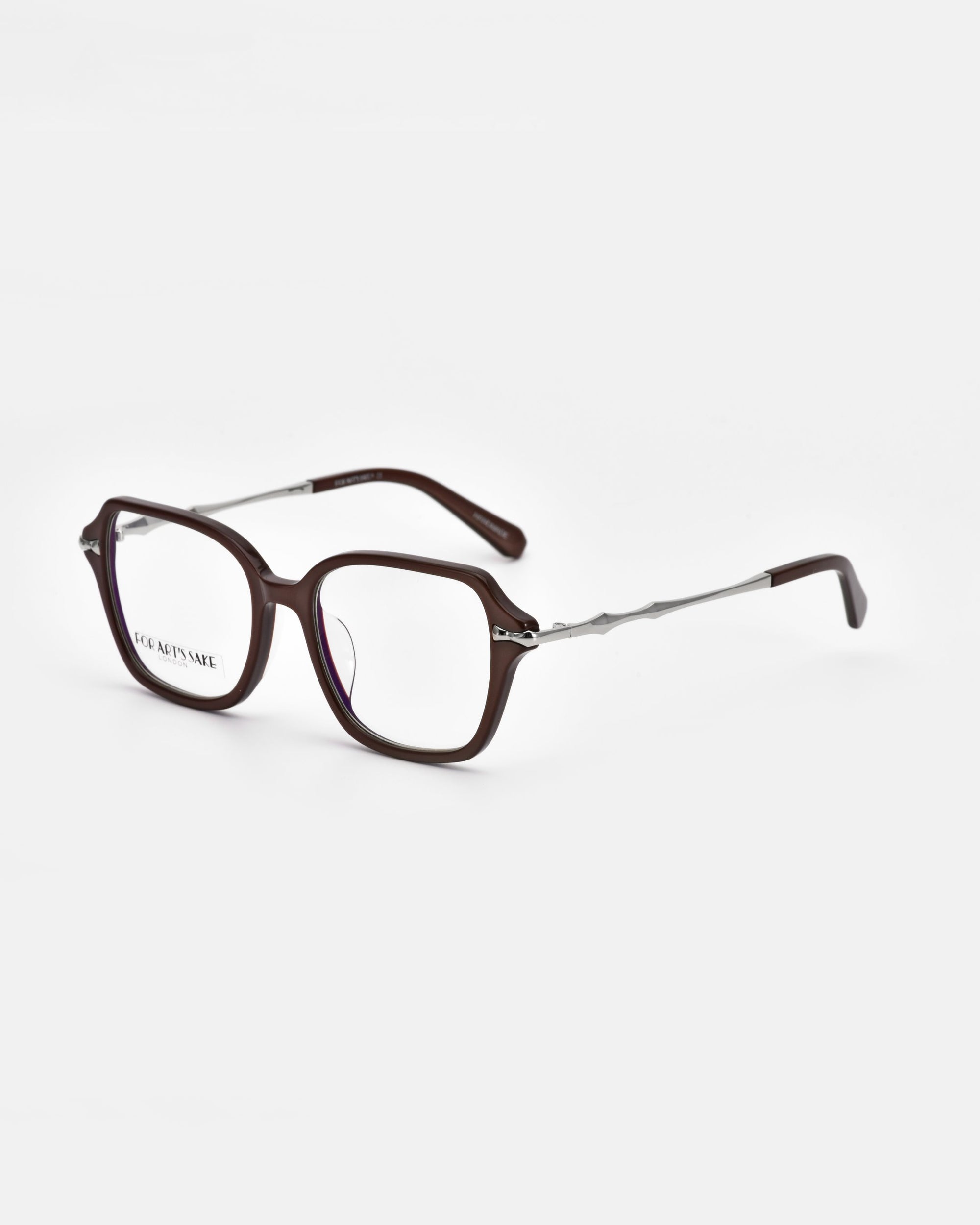 The &quot;Delight&quot; pair of square eyeglasses from For Art&#39;s Sake® boasts dark brown frames and long, thin temples. The temples feature a metallic section near the hinges, transitioning to a dark brown section at the ends. The clear lenses provide modern sophistication against a white background, evoking vintage charm.