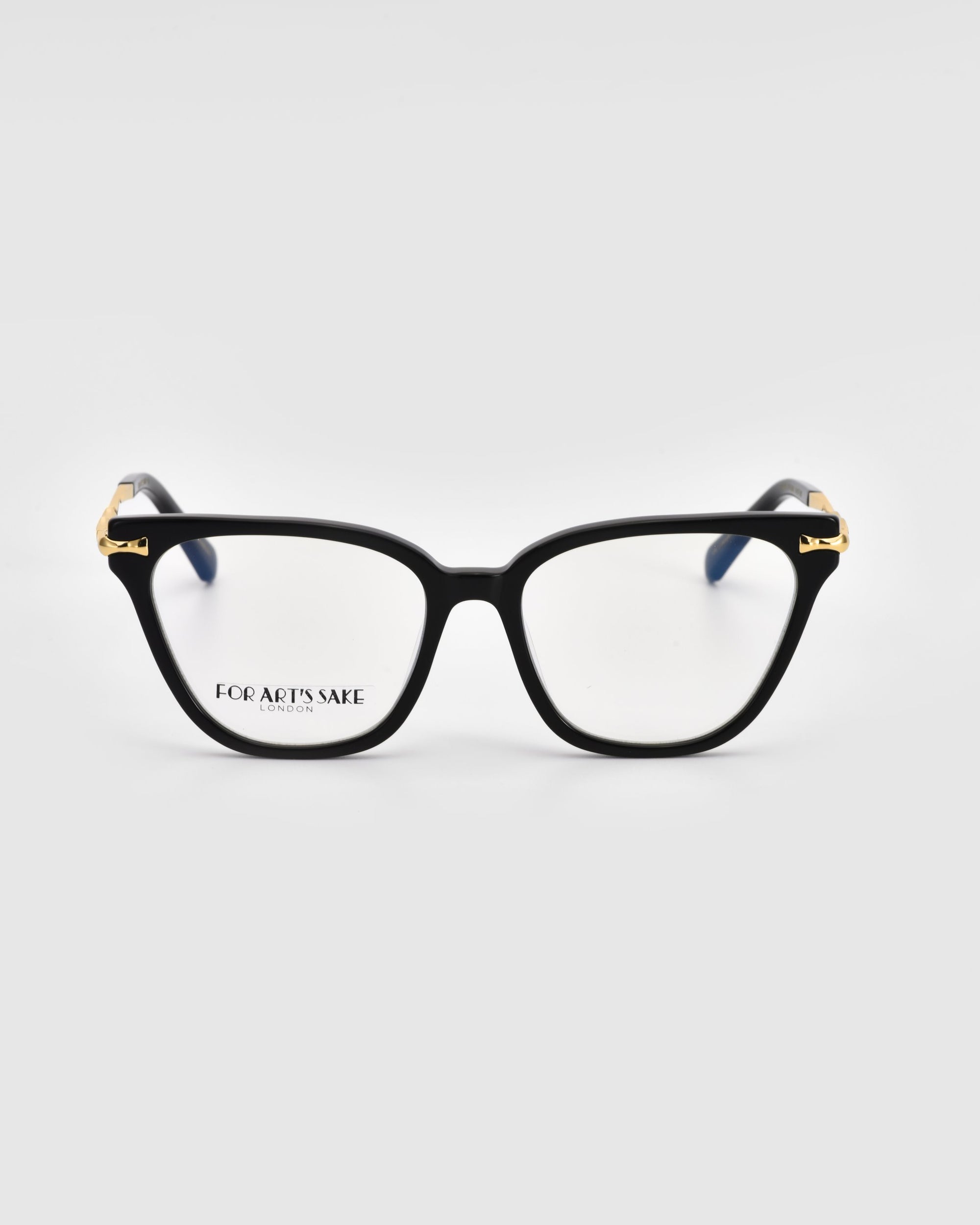 A pair of black-rimmed Lexie glasses with rectangular lenses, exuding modern sophistication. Designed by For Art&#39;s Sake®, the glasses feature gold accents on the corners and have &quot;FOR ART&#39;S SAKE LONDON&quot; printed on the inner edge of the left lens, all set against a plain white background.