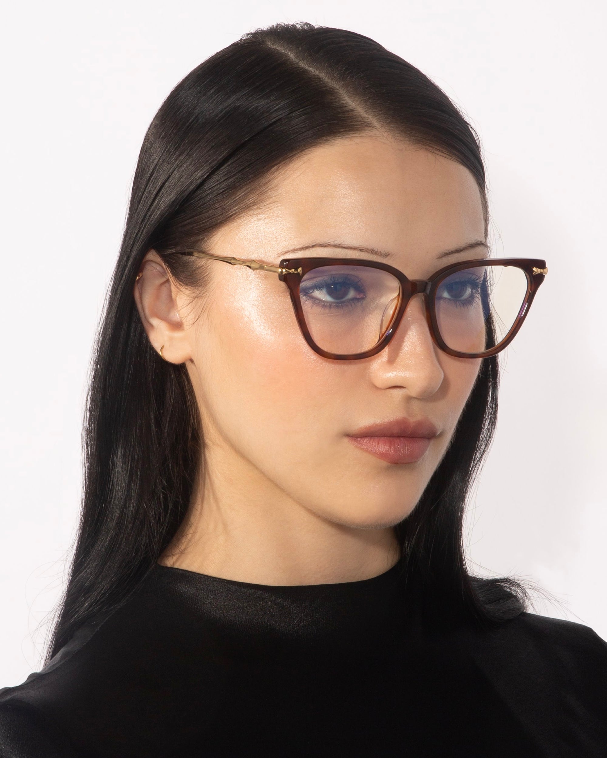 A woman with straight, dark hair and fair skin is wearing the Lexie cat-eye frames from For Art&#39;s Sake® that exude vintage charm. She looks slightly to the side with a neutral expression, set against a plain white background.