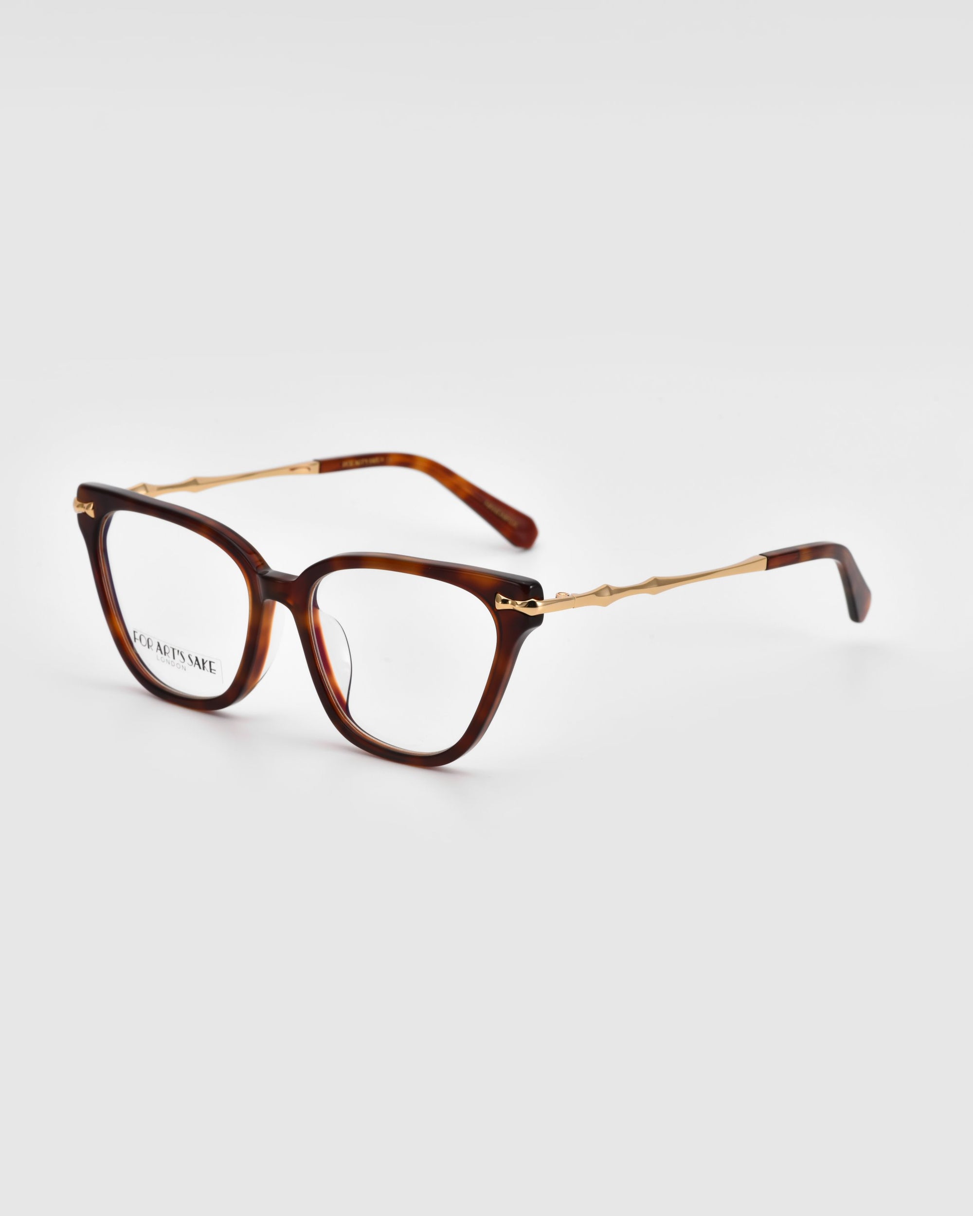 A pair of Lexie eyeglasses from For Art&#39;s Sake® featuring thick rectangular, brown tortoiseshell frames. The temples are gold-colored with a slender design, transitioning to brown towards the ear tips. The glasses are placed on a plain white background.