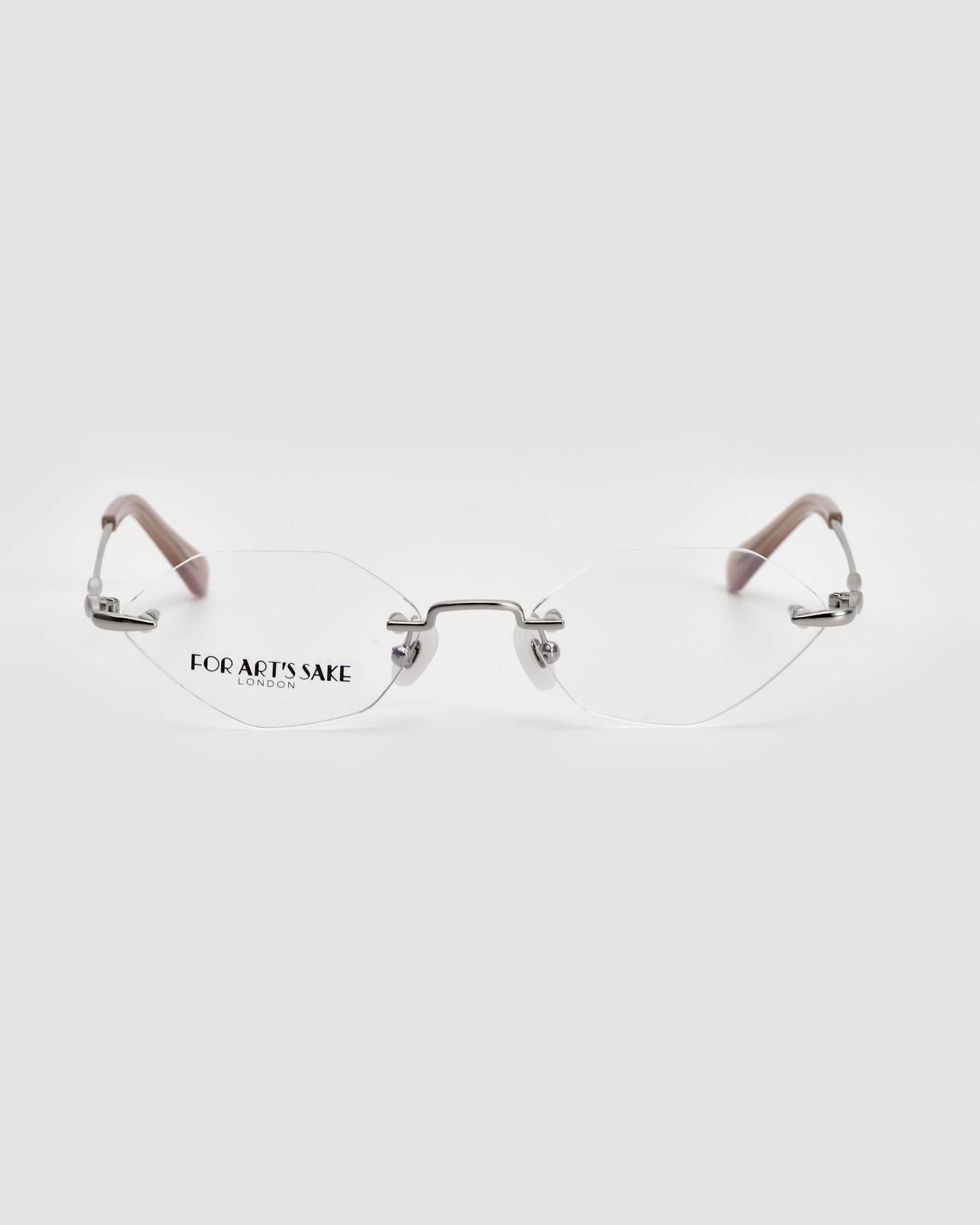 Introducing &quot;Zesty&quot; by For Art&#39;s Sake®: a pair of sleek, lightweight optical glasses featuring silver metal bridges and clear lenses. The temples are a rich brown color, while the left lens is adorned with the text &quot;FOR ART&#39;S SAKE LONDON.&quot; These frameless structure glasses certainly stand out against a light grey background.