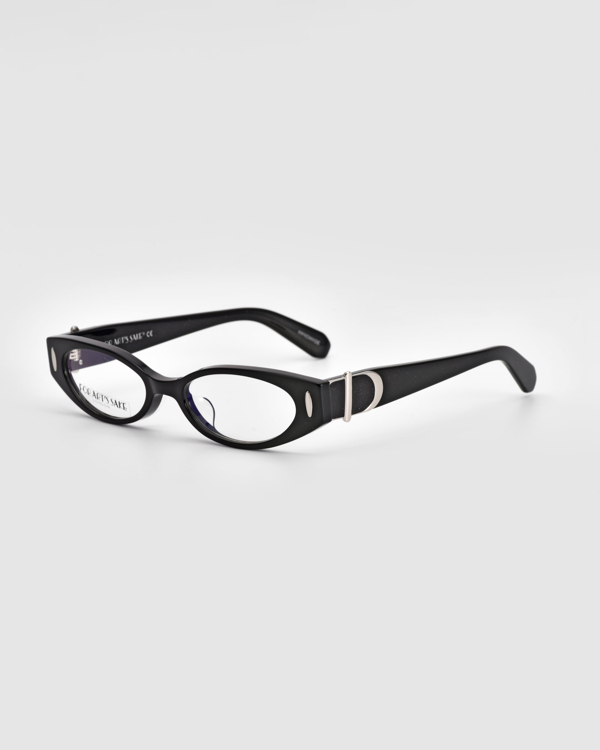 A pair of black rectangular eyeglasses with clear lenses exuding vintage charm. The frames, adorned with silver accents on the temples near the hinges, blend sophistication and style. Made from polished acetate, the Cigar frames by For Art's Sake® stand out against the plain light gray background.