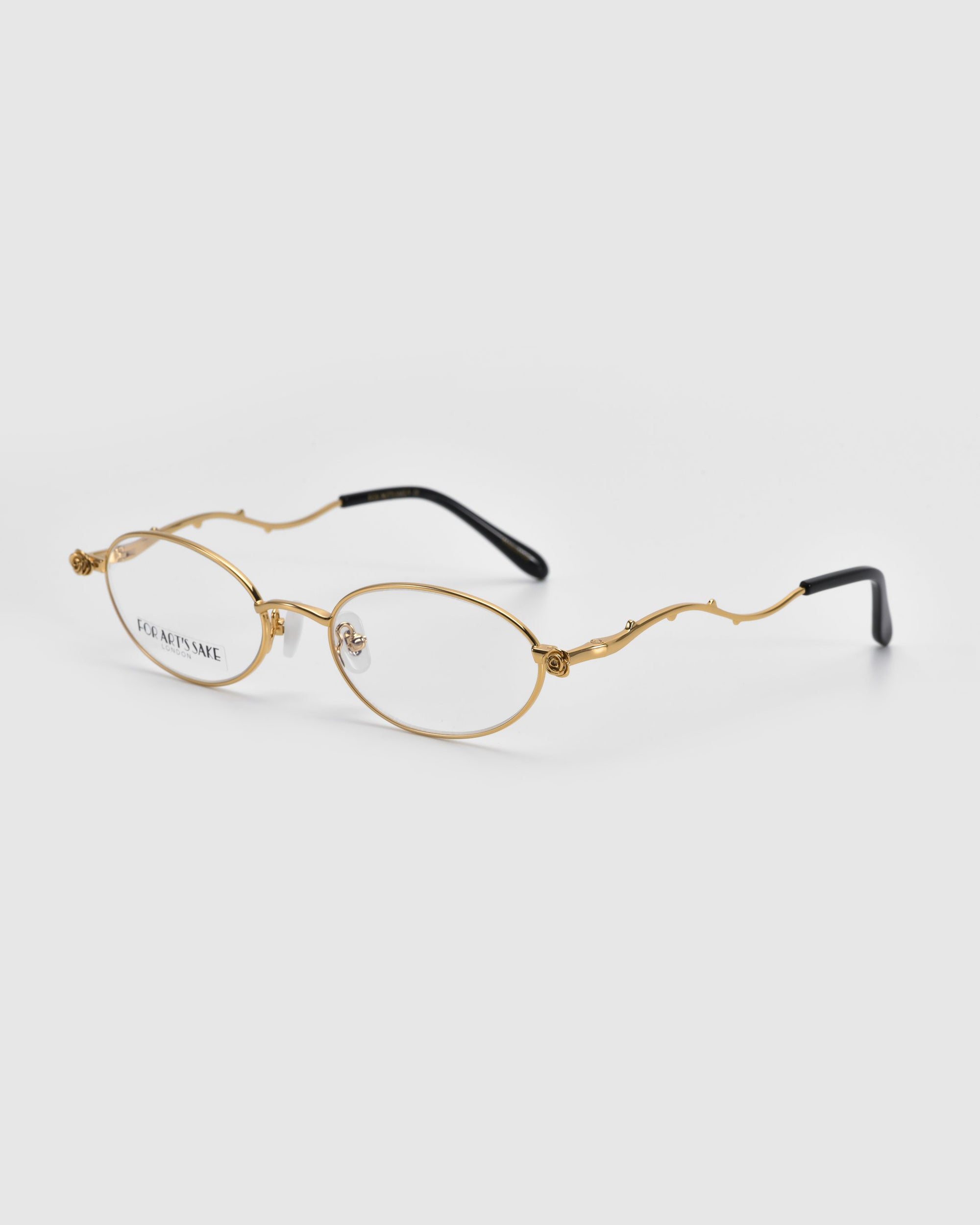 For Art's Sake® presents Thorn: gold oval wireframe optical glasses with curved arms and black tips on a white background. These glasses showcase artistic expression with their delicate, minimalist design, positioned with the lenses facing forward.