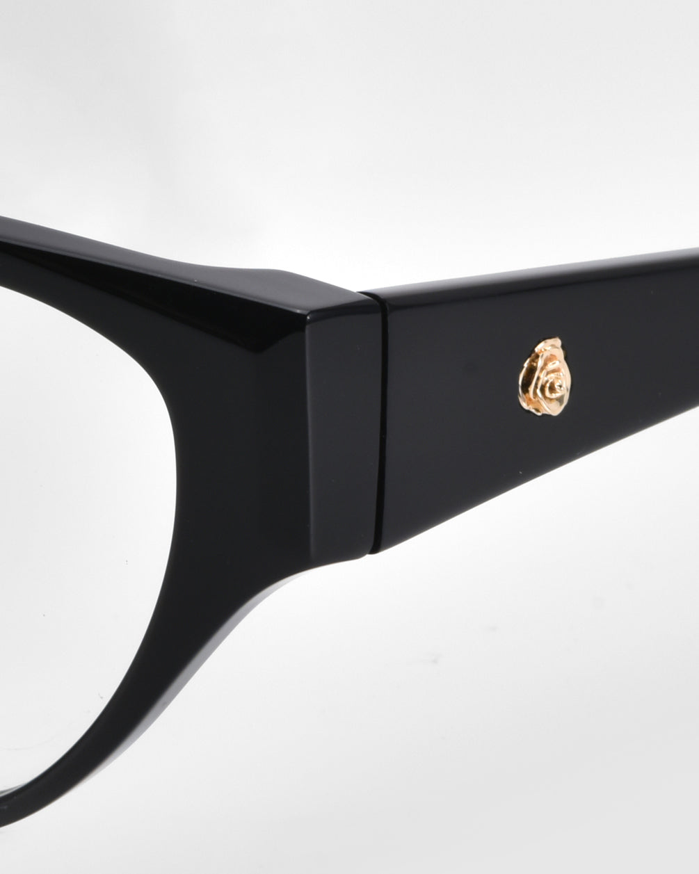 Close-up of the side of For Art's Sake® Rosalia I eyeglasses from the Rose Garden Collection, featuring a sleek black design with a gold rose emblem on the temple, highlighting elegance and charm around the hinge area.