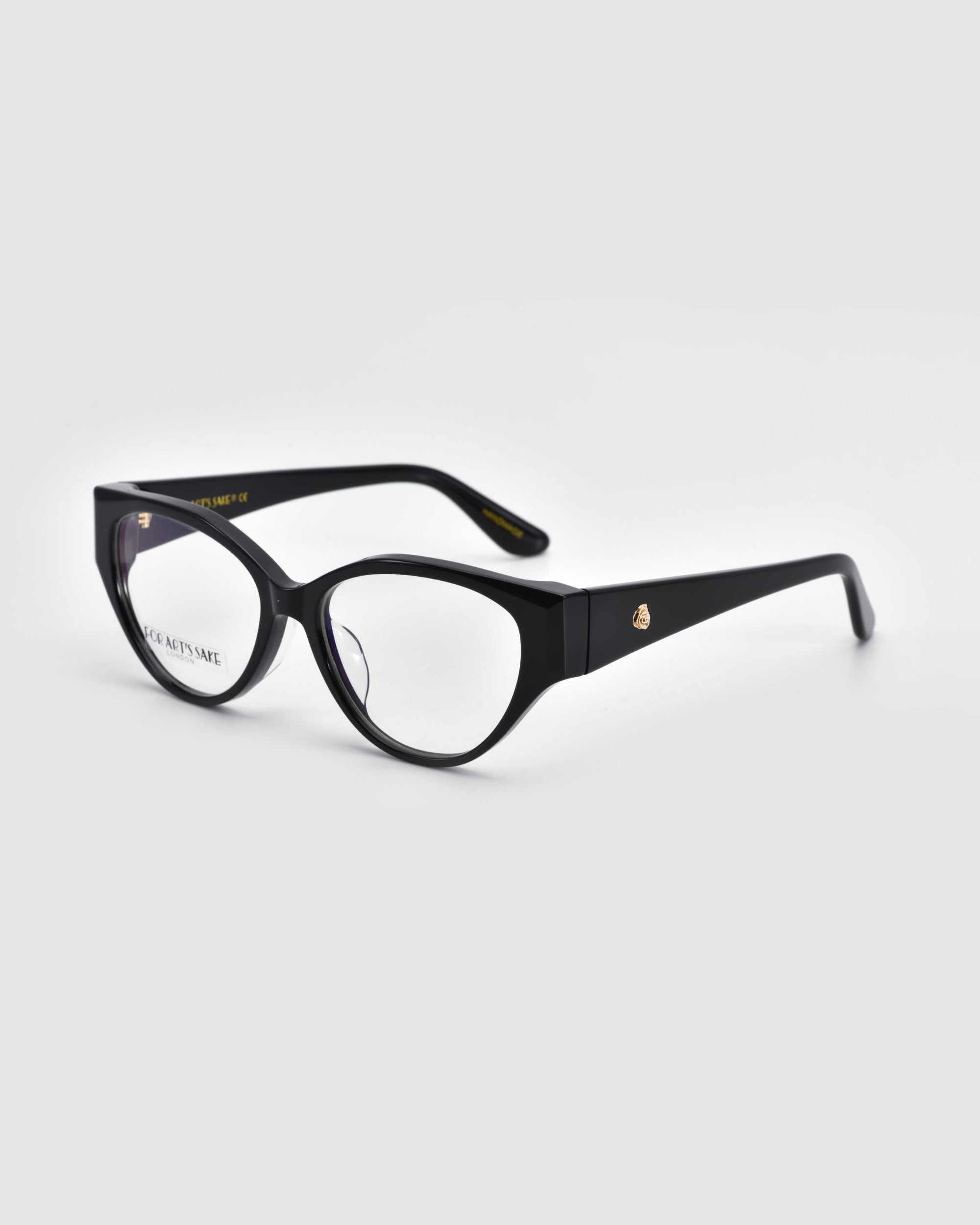 The Rosalia I cat-eye optical frame by For Art's Sake® features black rims and clear lenses, exuding femininity. A small gold logo adorns the arms. Part of the Rose Garden Collection, they rest against a light gray background, angled to show both sides.