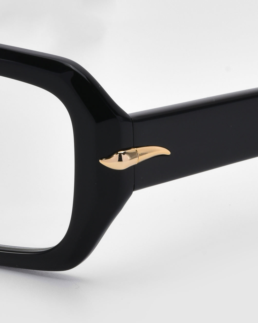 Close-up of the For Art&#39;s Sake® &quot;Petal&quot; glasses frame in black, featuring a gold, horn-shaped embellishment on the temple. This minimalist design offers a versatile look that complements any style. The background is plain white.