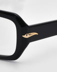 Close-up of the For Art's Sake® "Petal" glasses frame in black, featuring a gold, horn-shaped embellishment on the temple. This minimalist design offers a versatile look that complements any style. The background is plain white.