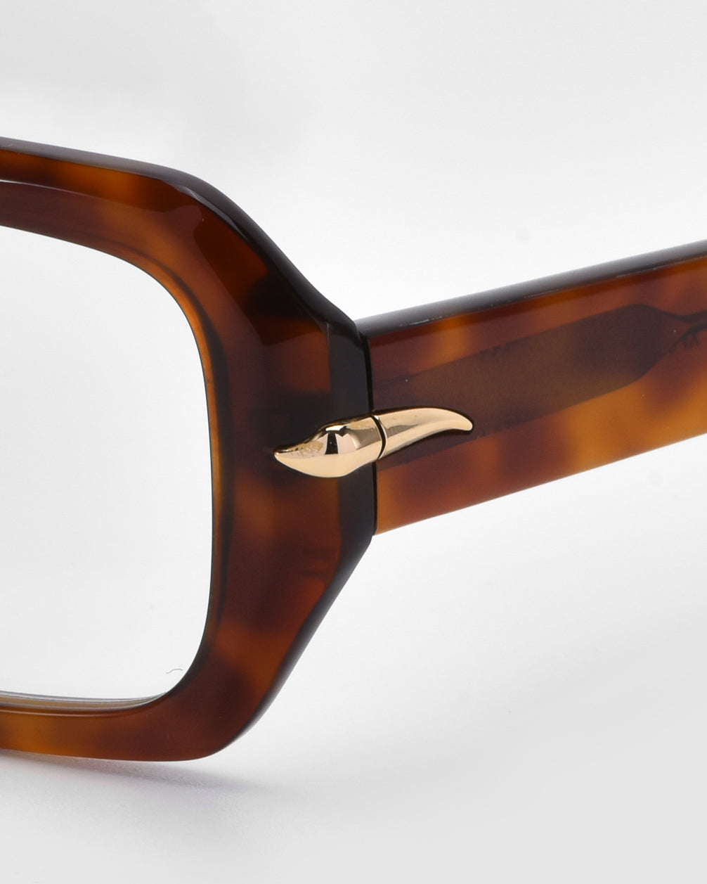 Close-up of For Art's Sake® Petal eyeglasses with a bold, rectangular tortoiseshell acetate frame and gold decorative temple element. The plain white background highlights the design, subtly elegant like rose petals.