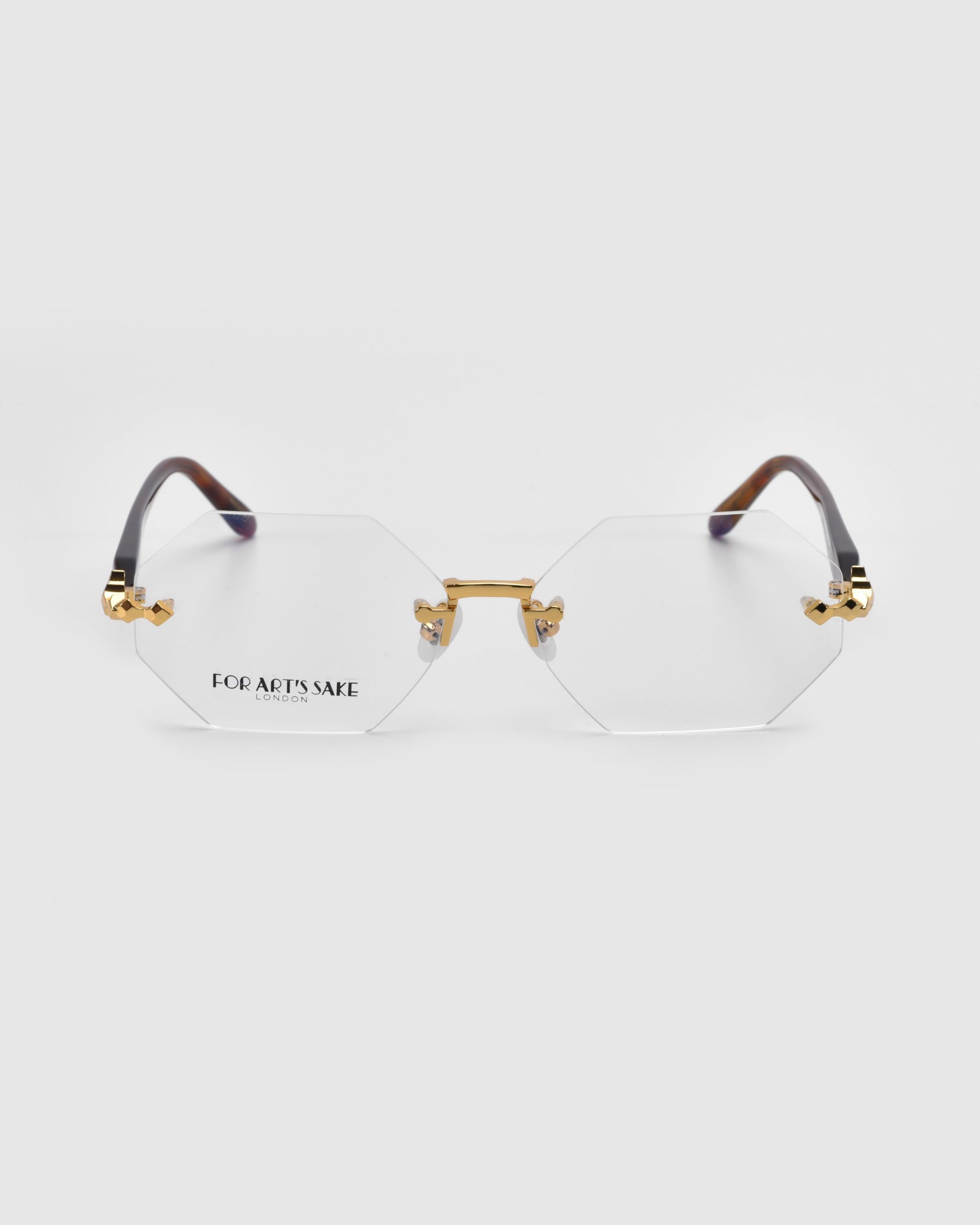 From the Rose Garden collection, "Hampton" by For Art's Sake® boasts gold hexagonal frames with clear lenses on a white backdrop. The black temples are highlighted in gold, and the brand's logo adorns the left lens, perfectly blending elegance and style for any occasion.