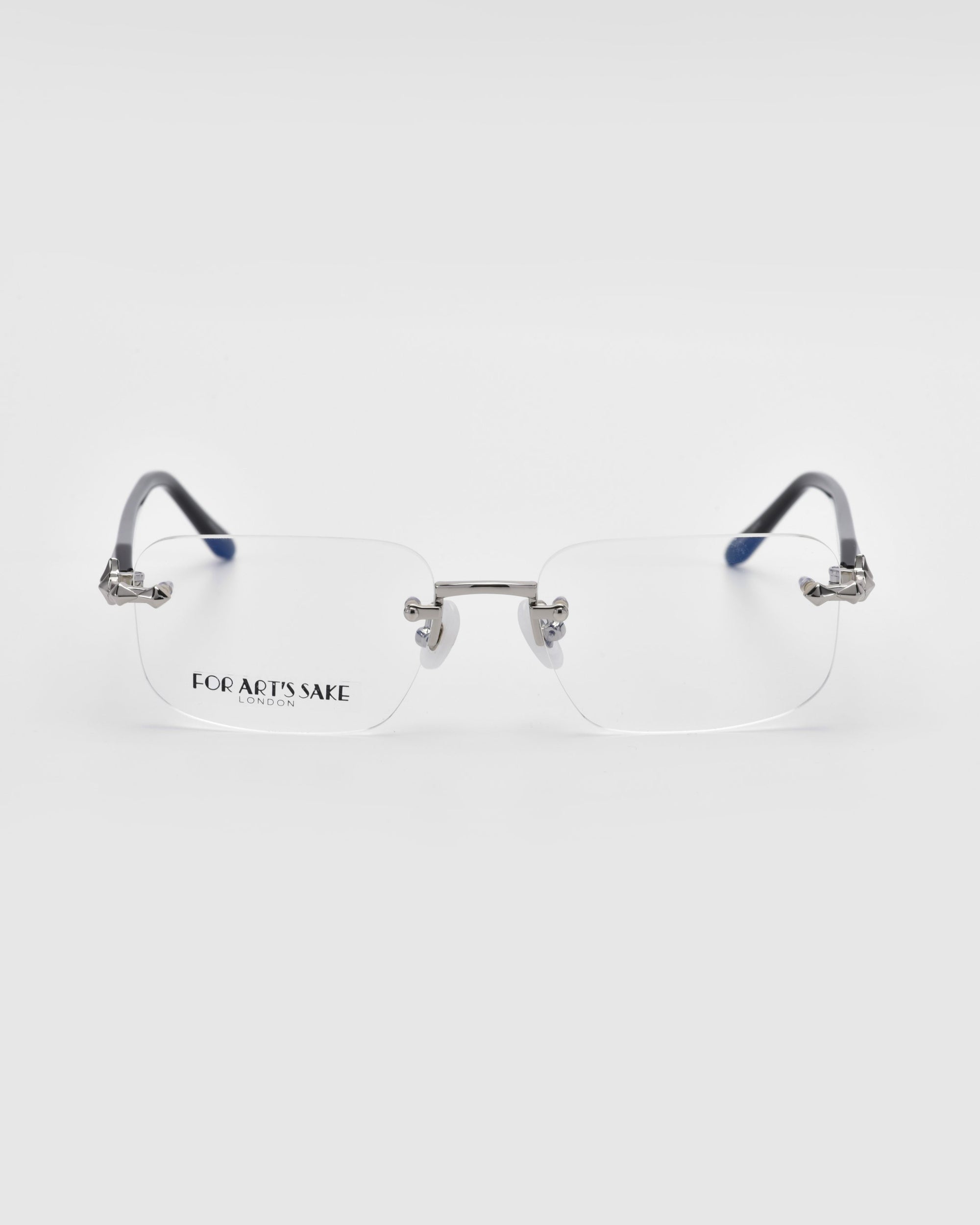 The Claremont eyeglasses from For Art's Sake® feature rimless lenses, silver temples, and clear nose pads set against a white background. The left rectangular lens is adorned with a "For Art's Sake London" logo in sleek black lettering for an elegant touch.